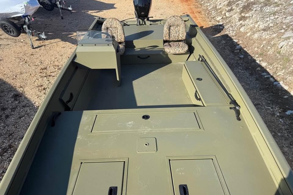 2026 Lowe Roughneck 2070 boat with camouflage seats, parked on gravel.