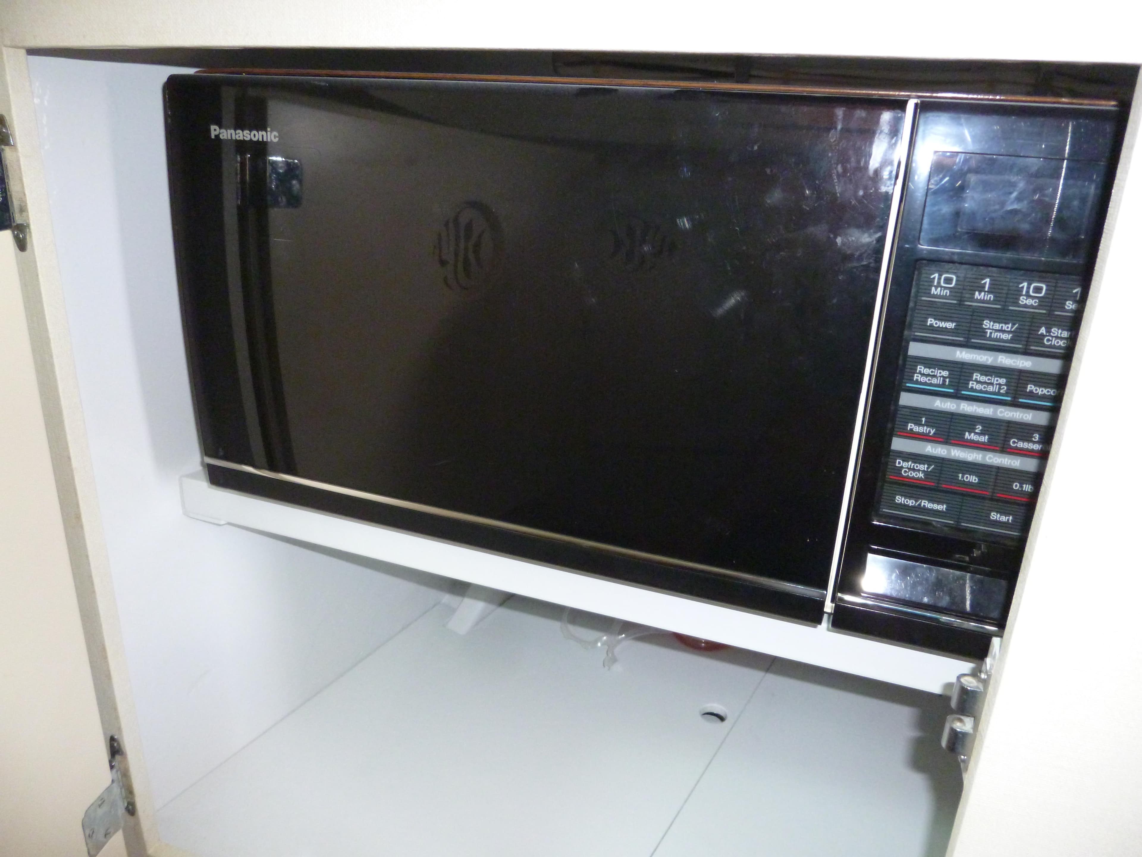 Panasonic microwave oven with digital controls, installed in a kitchen cabinet.