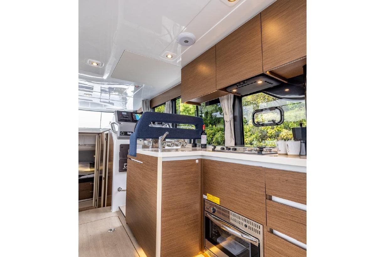 Modern kitchen interior of 2026 Delphia 11 Flylounge yacht with wood cabinetry and appliances.