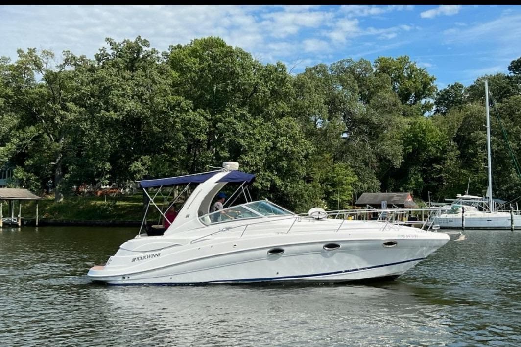2006 Four Winns 318 Vista boat cruising on a serene lake with lush greenery.