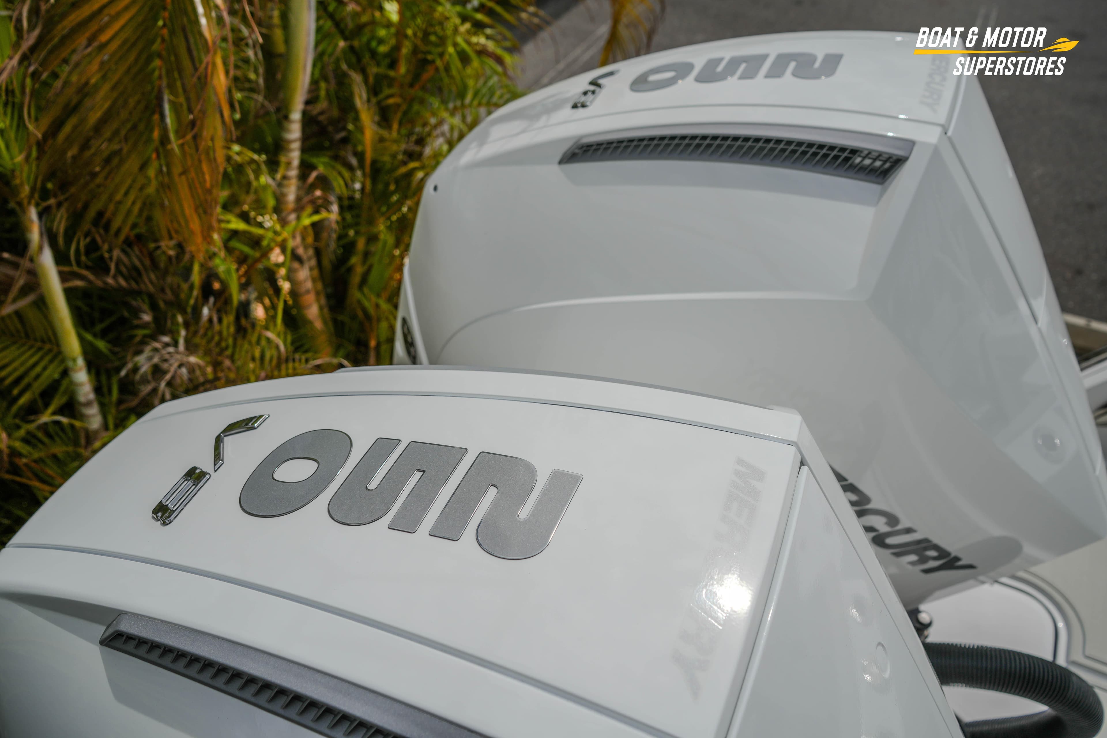 Twin Mercury outboard engines on a 2026 Blackfin 272 DC boat, with tropical foliage background.