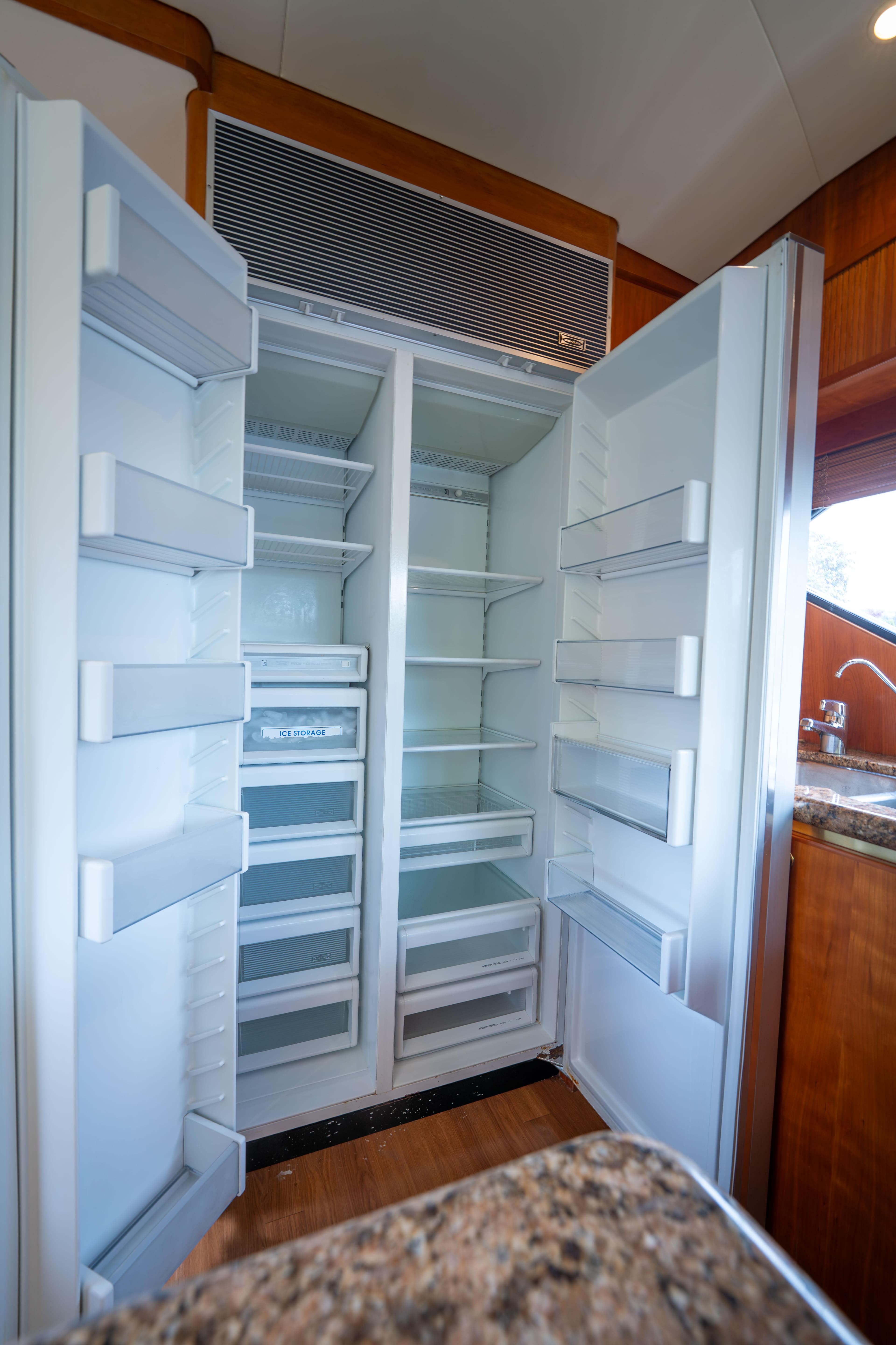 Open refrigerator in 2001 West Bay 58 RPH yacht kitchen, showcasing spacious interior and shelving.