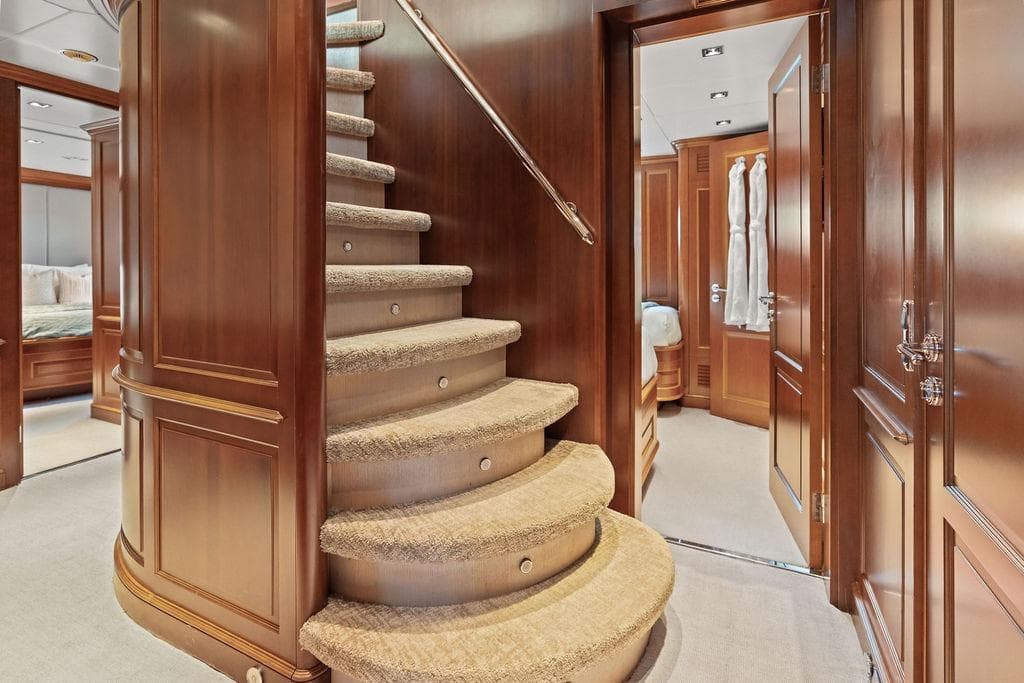 Luxurious interior of 2008 Benetti Classic yacht featuring elegant wooden staircase and plush carpeting.