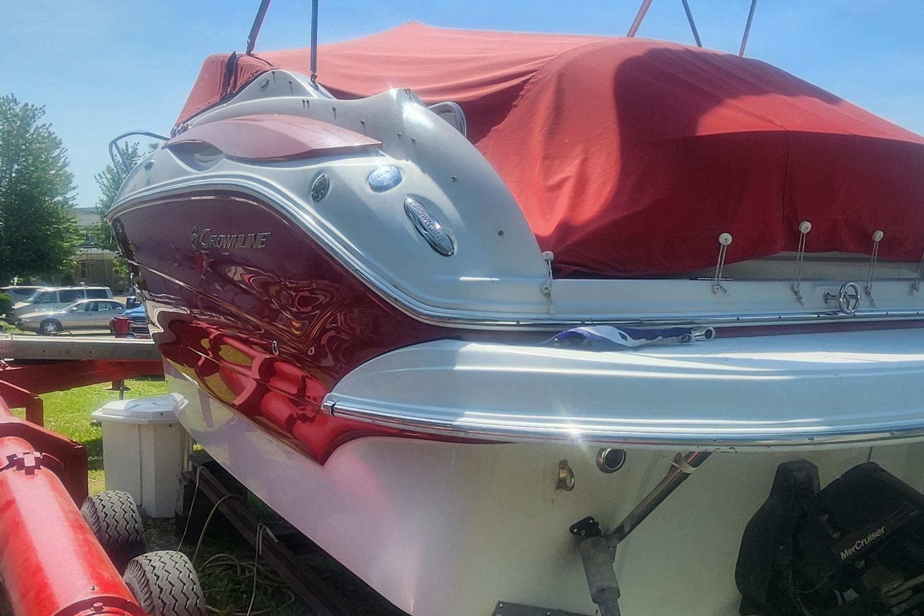 2009 Crownline 250CR boat with red cover on trailer, parked outdoors.