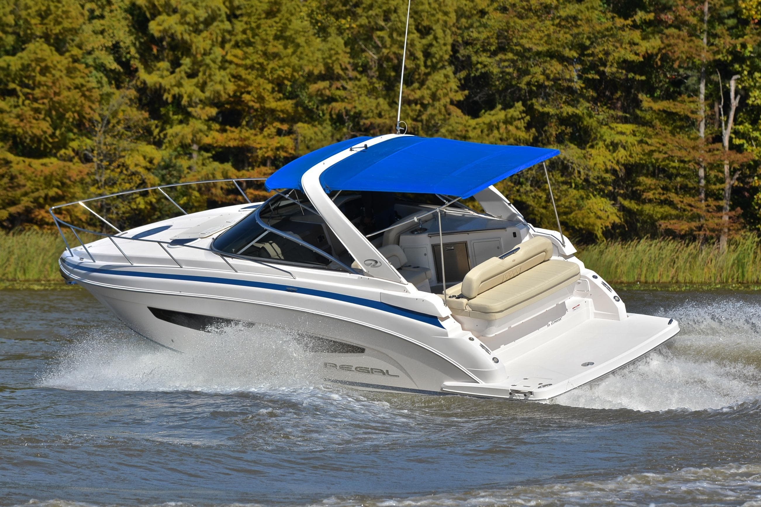 2018 Regal 33 Express boat cruising on a lake with a blue canopy.