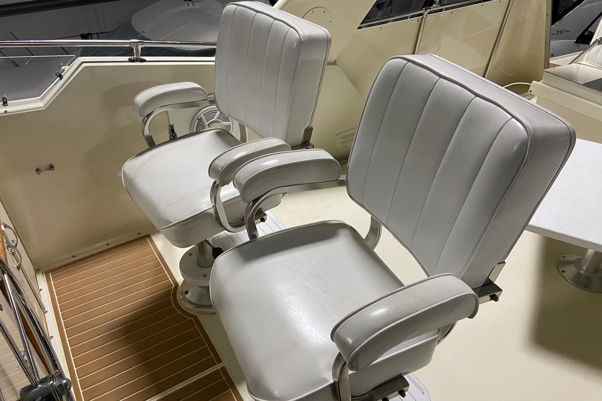 Two white captain's chairs on a 1985 Hatteras 53 Motor Yacht deck.