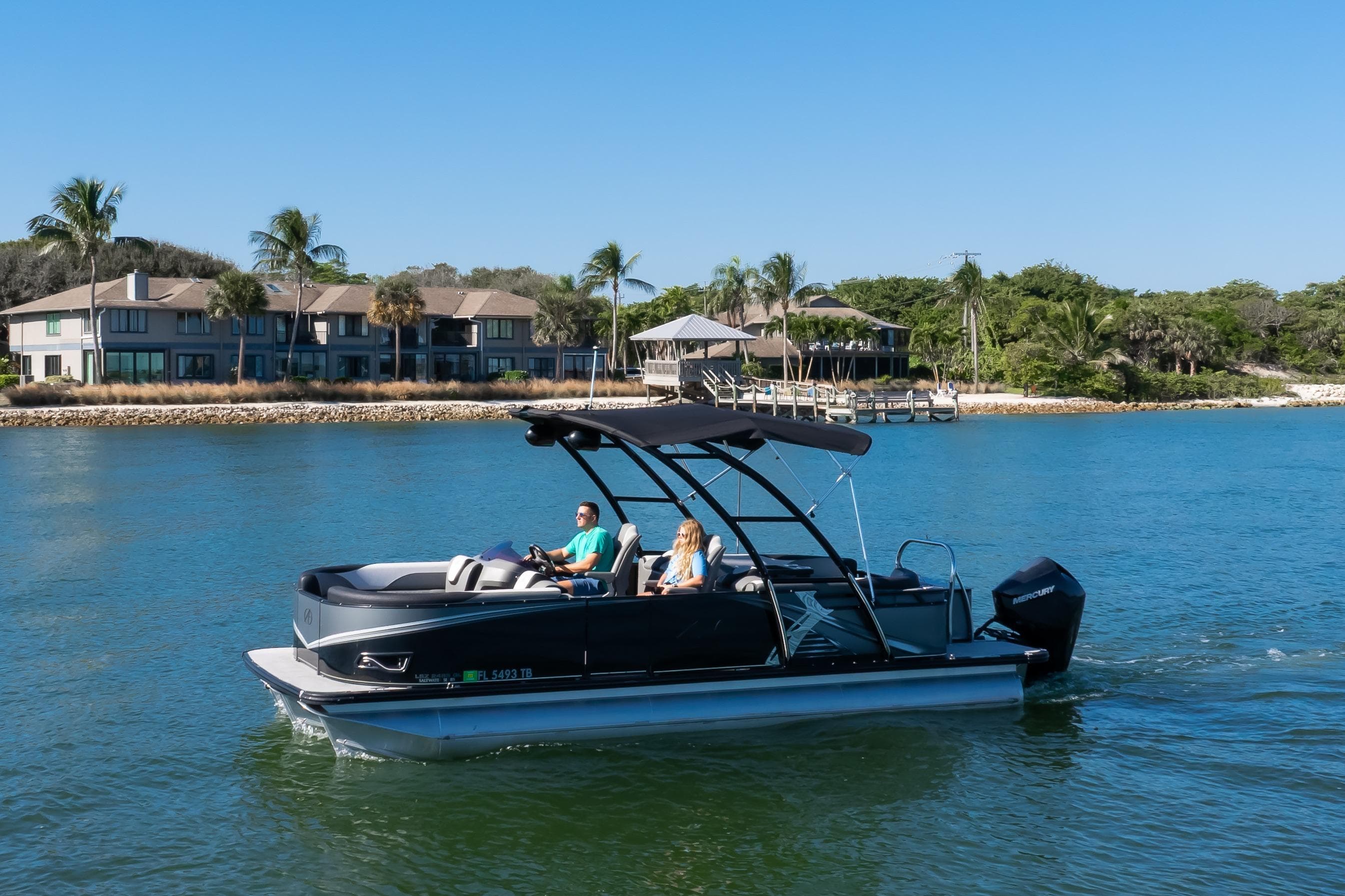 2021 Avalon LSZ Quad Lounger boat cruising on a sunny day near waterfront homes.