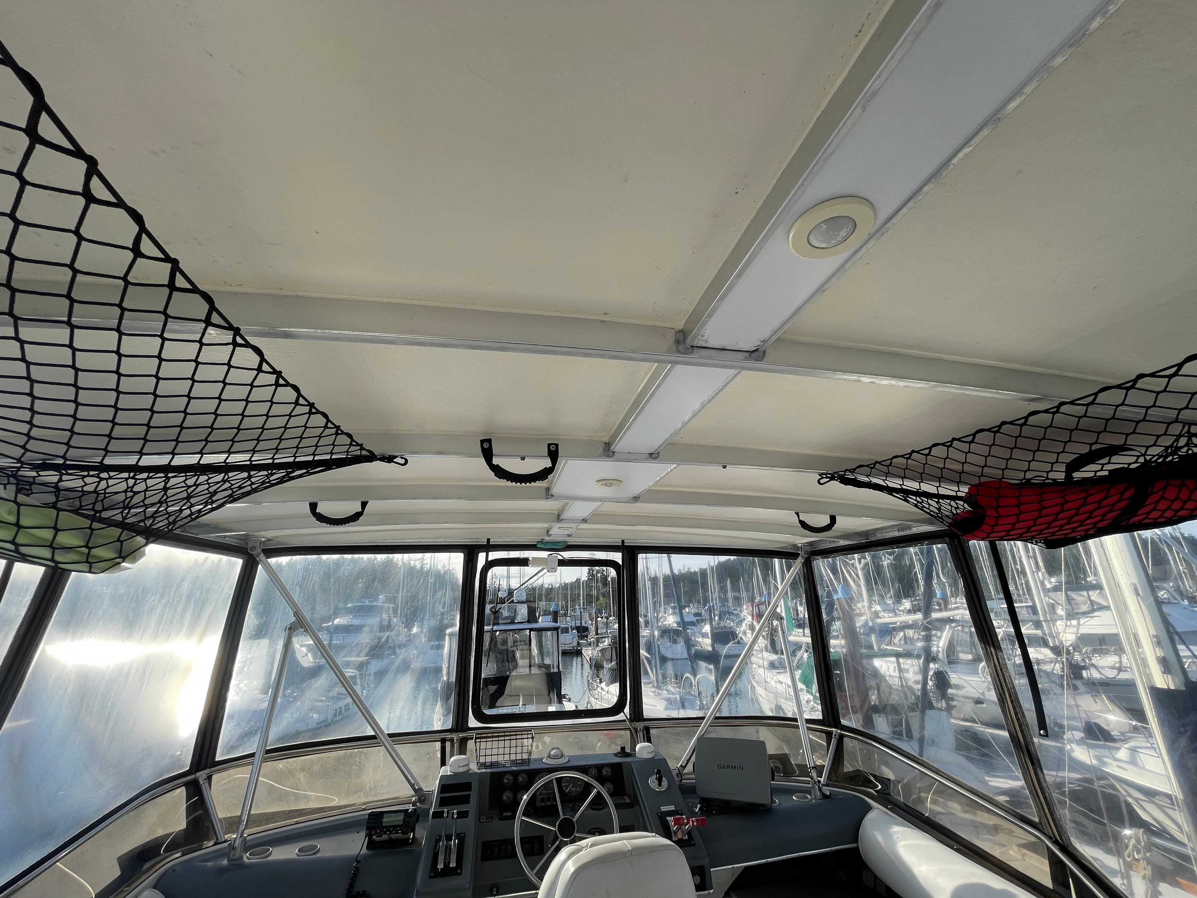 Interior view of 1991 Bayliner 4387 boat cockpit with steering wheel and overhead storage nets.