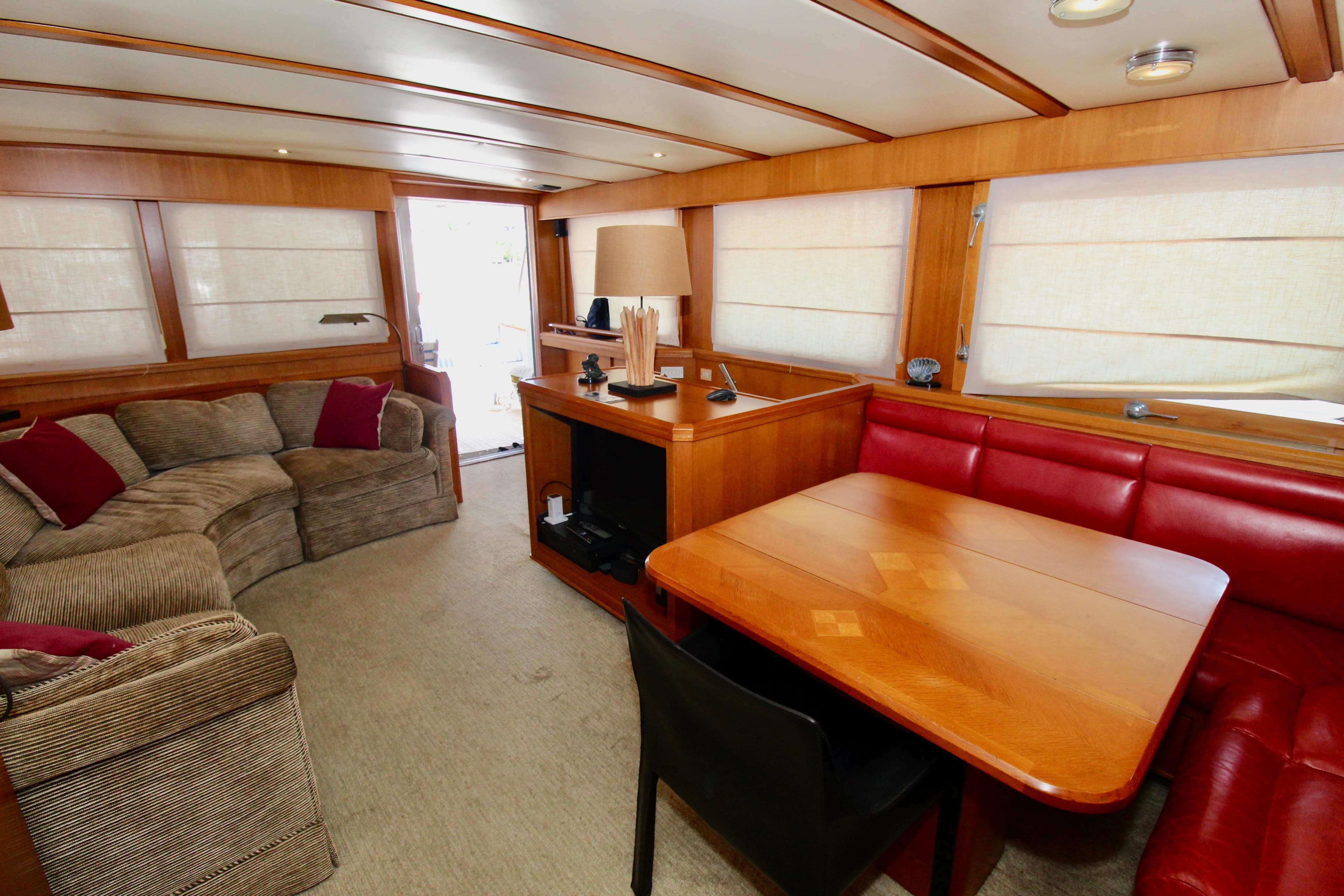 Luxurious 1990 Hakvoort Motor Yacht interior with cozy seating and elegant wooden dining area.
