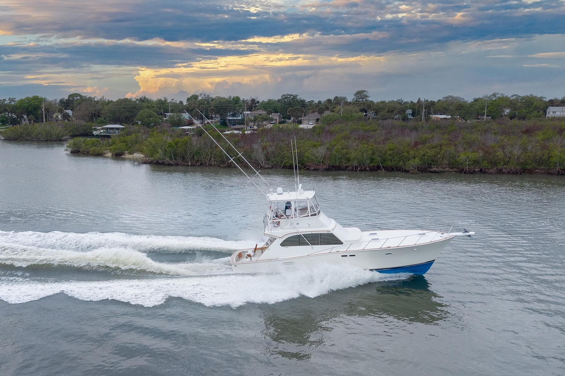 1982 Post 46 Convertible yacht cruising on a scenic river at sunset.