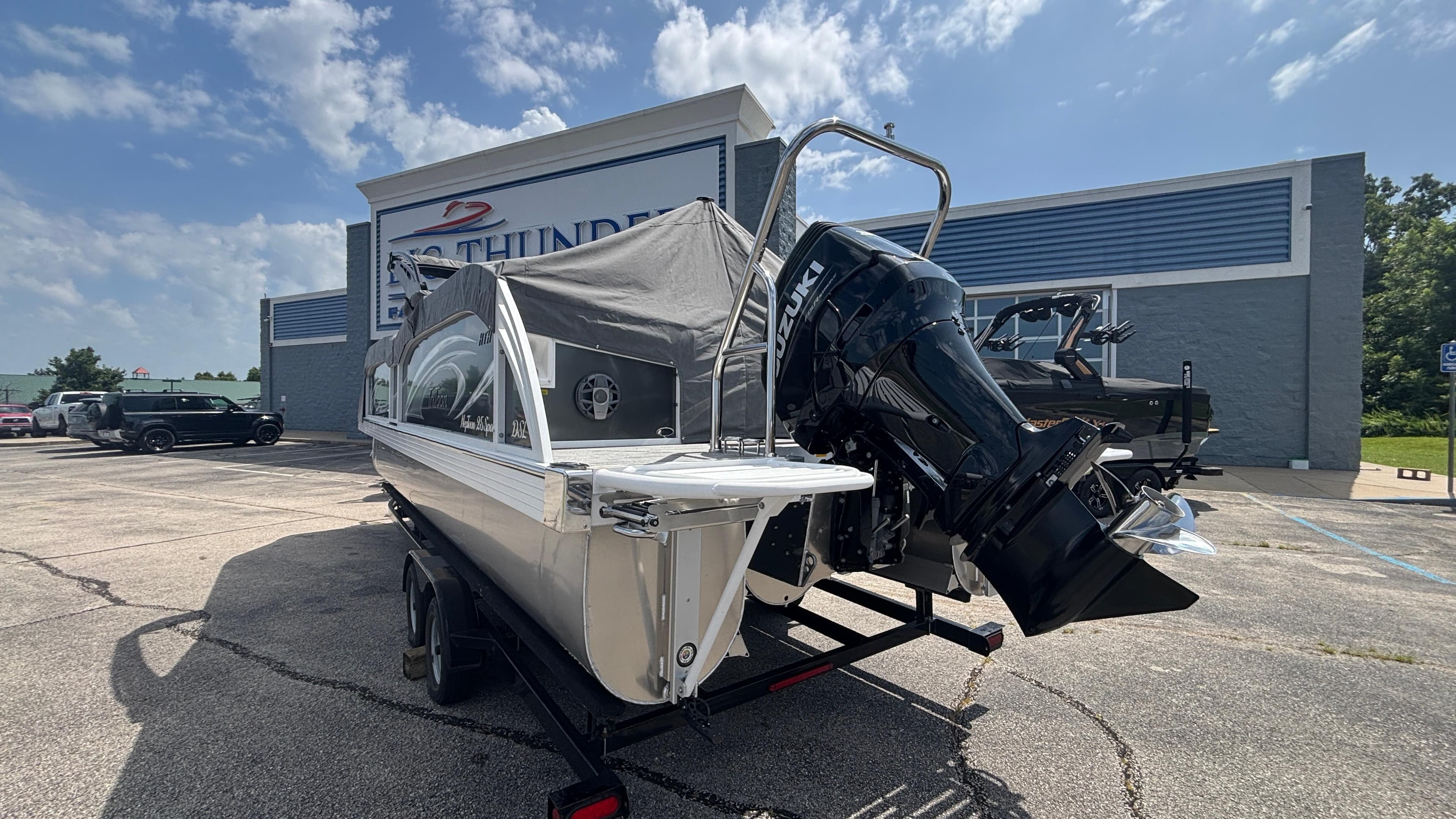 2025 JC Neptoon 25TT Sport boat with Suzuki outboard motor at dealership.
