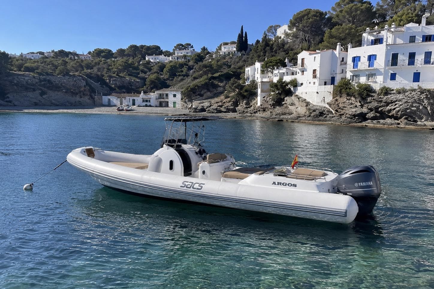 2009 SACS Stratos 12 boat anchored in scenic coastal waters with white buildings.