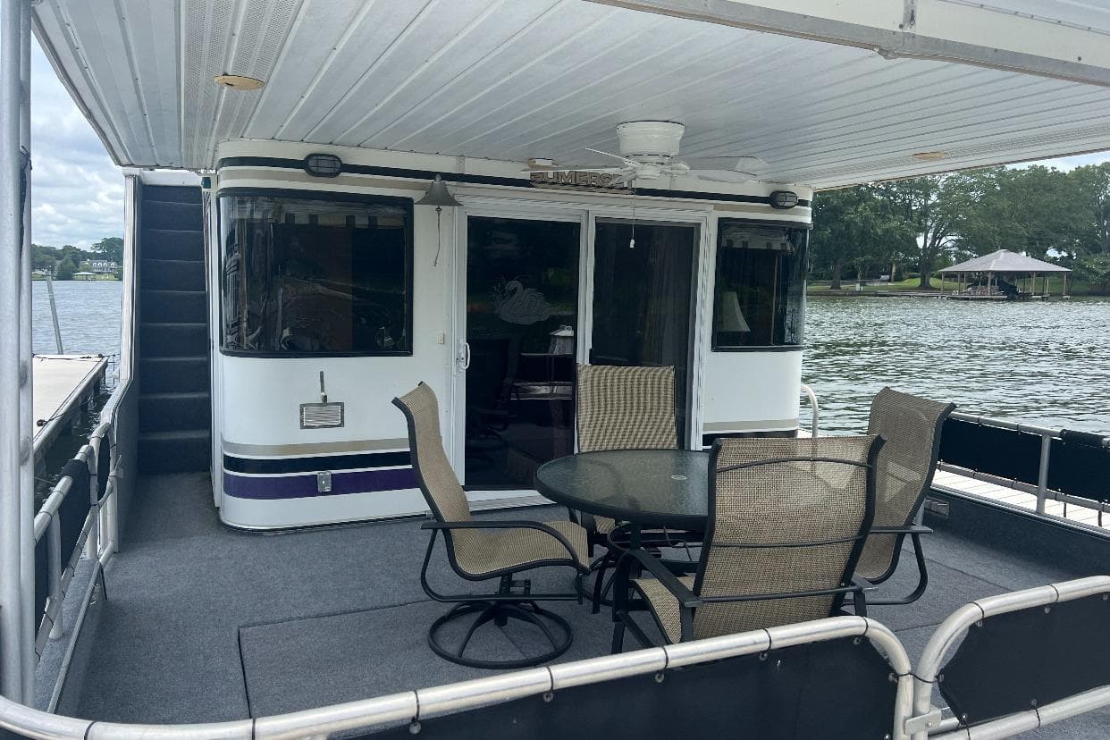 1998 Sumerset 16x80 houseboat with outdoor seating on a serene lake.
