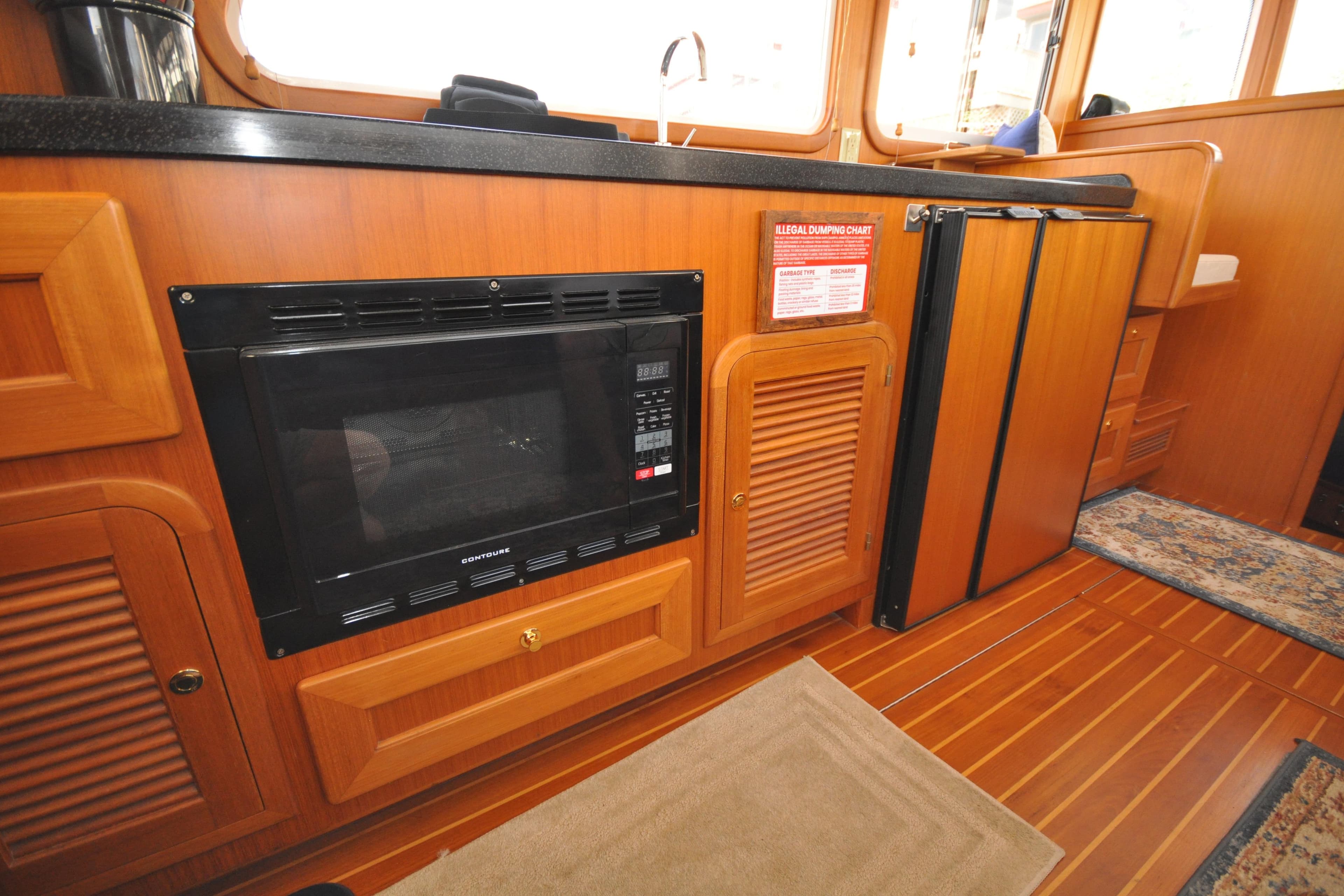 2015 Helmsman Trawlers 31 Sedan interior with microwave and wooden cabinetry.
