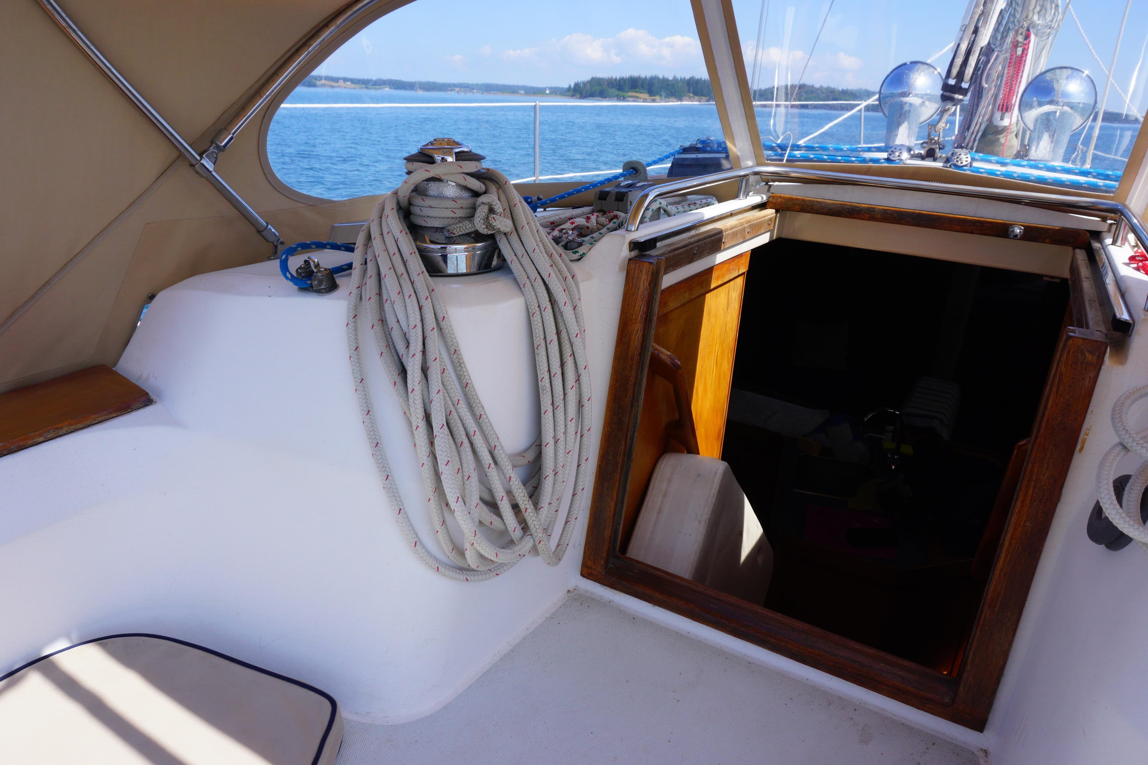 1998 Sabre 402 sailboat cockpit with ropes, open hatch, and ocean view.