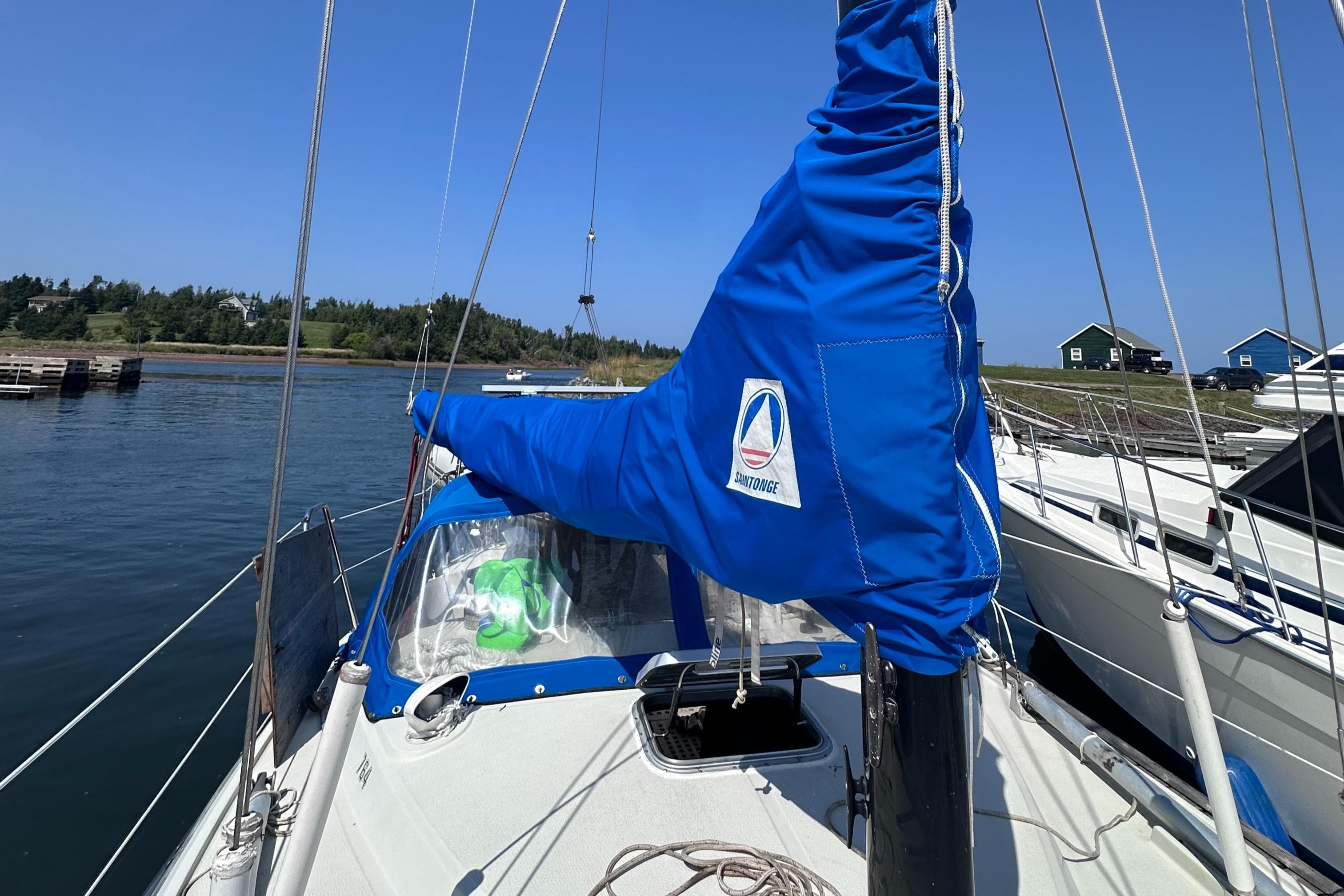 1978 Maxi 95 sailboat docked, featuring blue sail cover and scenic waterfront background.