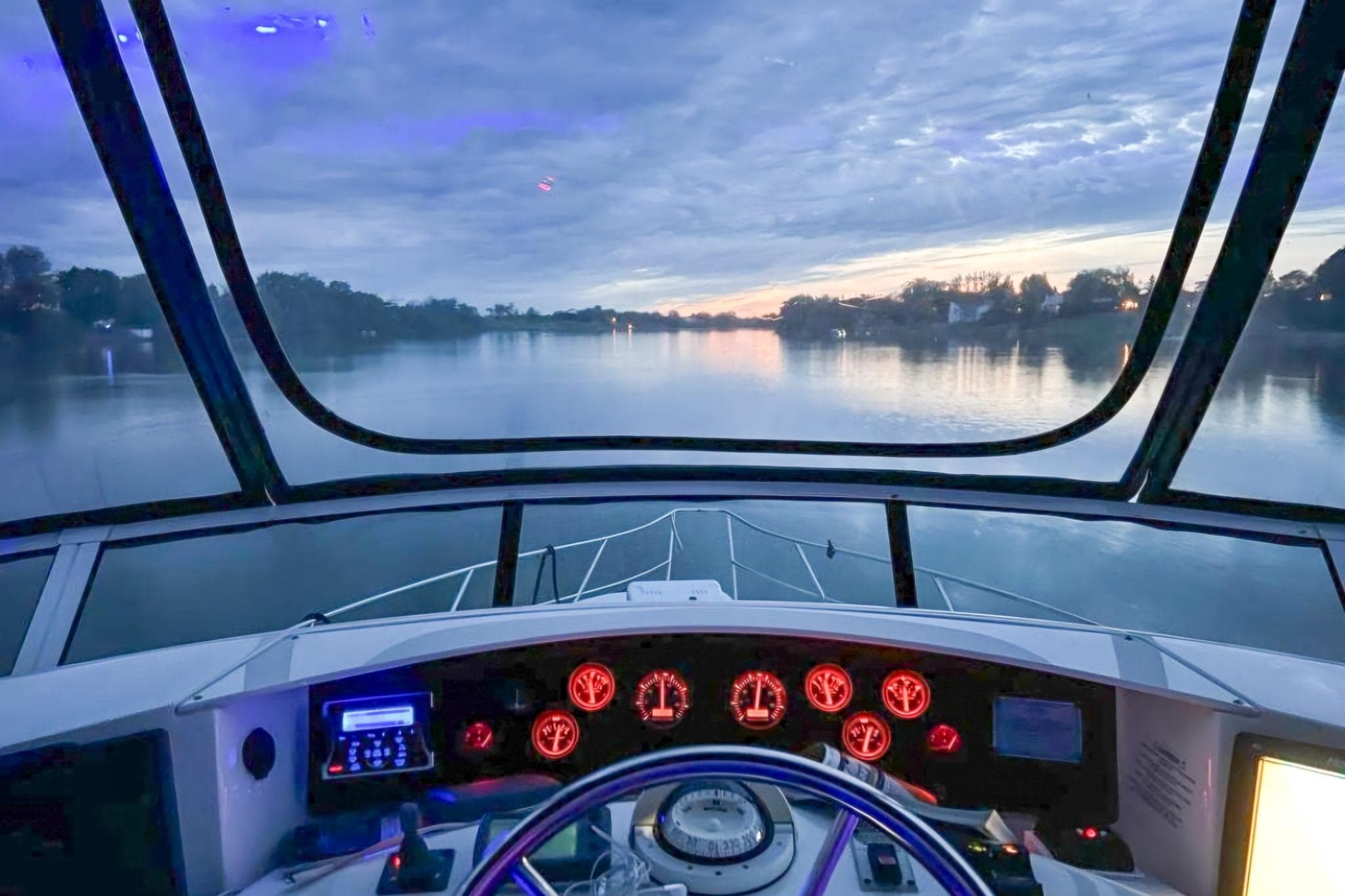 Cockpit view from 2005 Silverton 39 Aft Cabin yacht at sunset on a serene river.