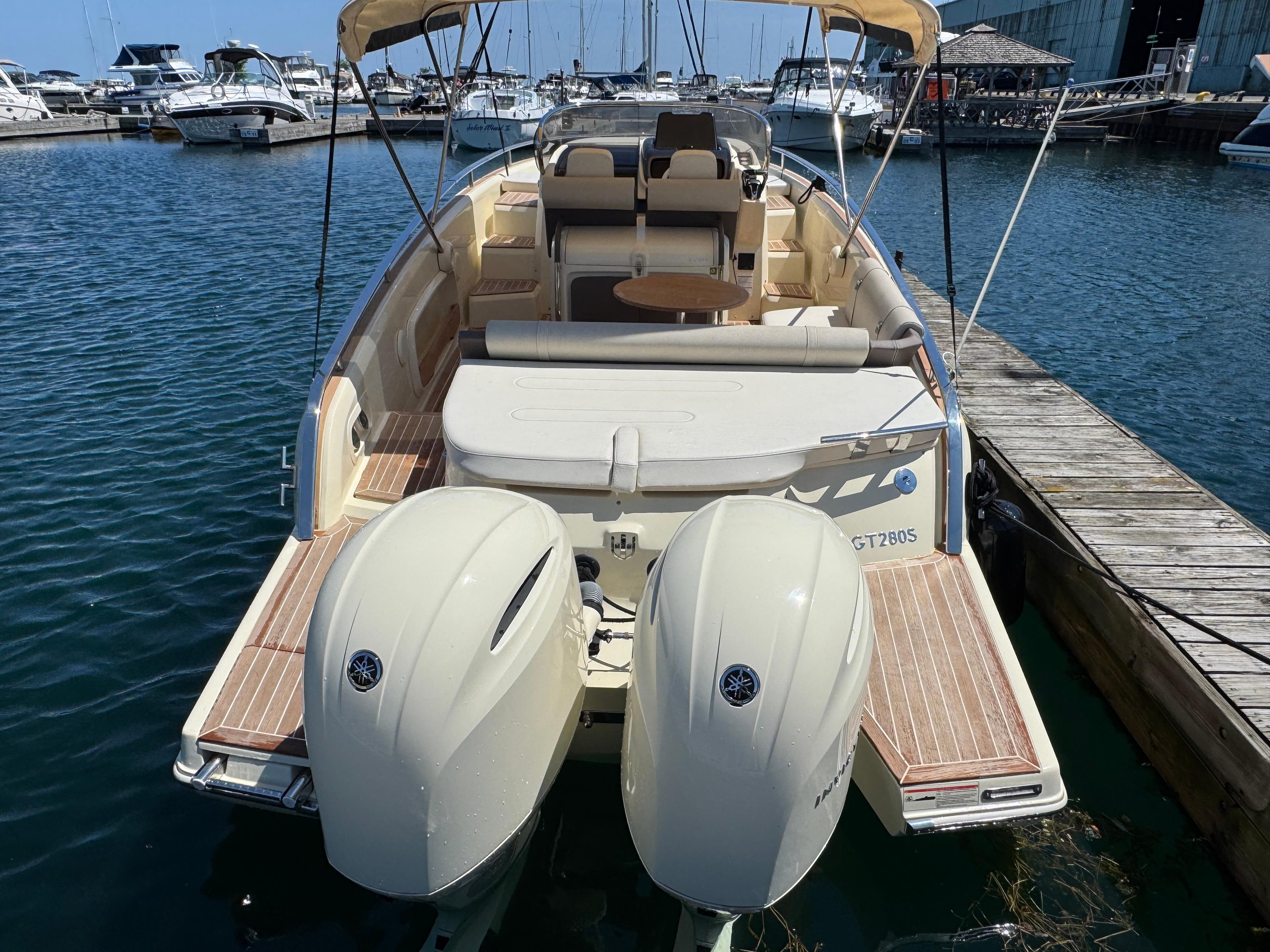 2023 Invictus GT 280S boat docked at marina, featuring dual outboard engines.