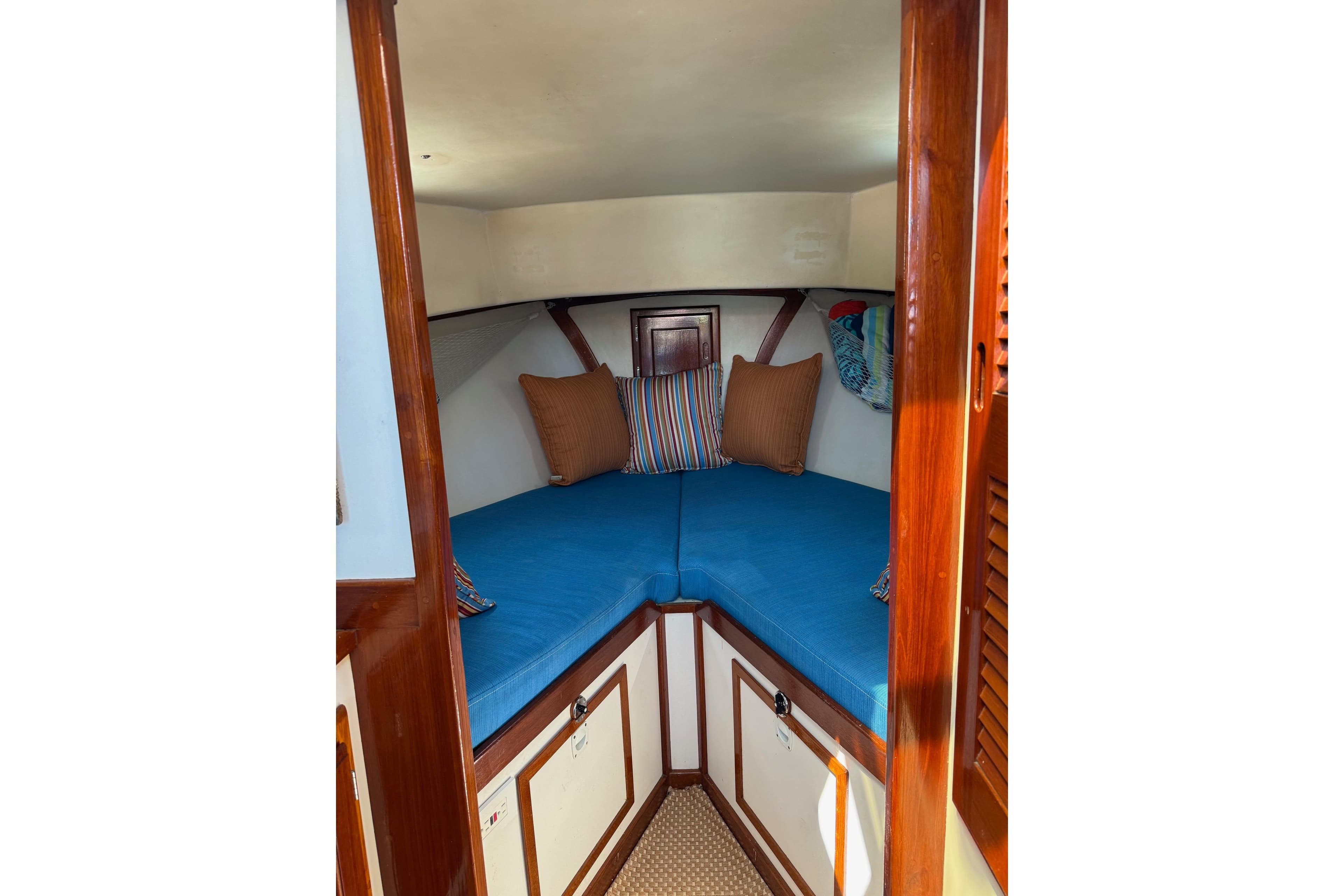 Cozy cabin interior of a Duffy 26 boat with blue cushions and wooden accents.