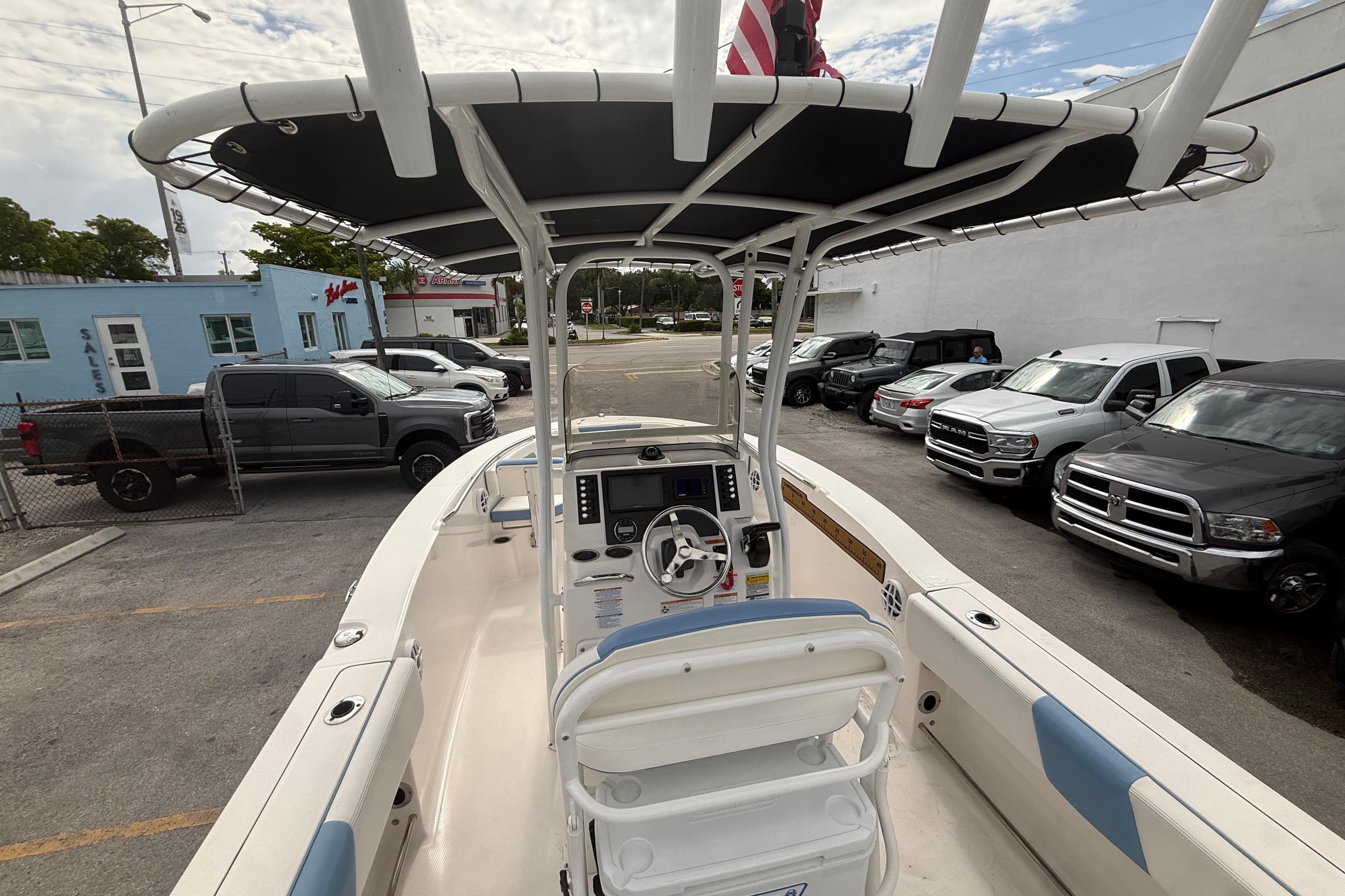 2023 Robalo R202 Explorer boat with T-top, parked near vehicles.