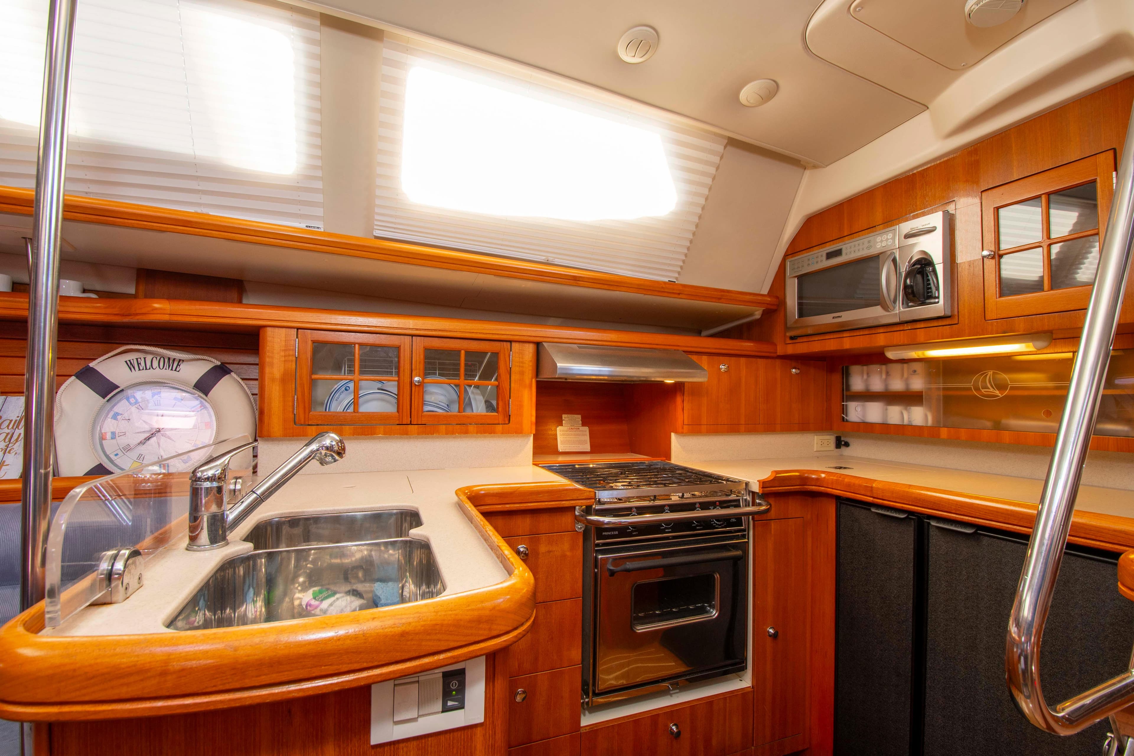 2005 Hunter 45 CC yacht kitchen with wood cabinetry, stainless steel sink, stove, and microwave.
