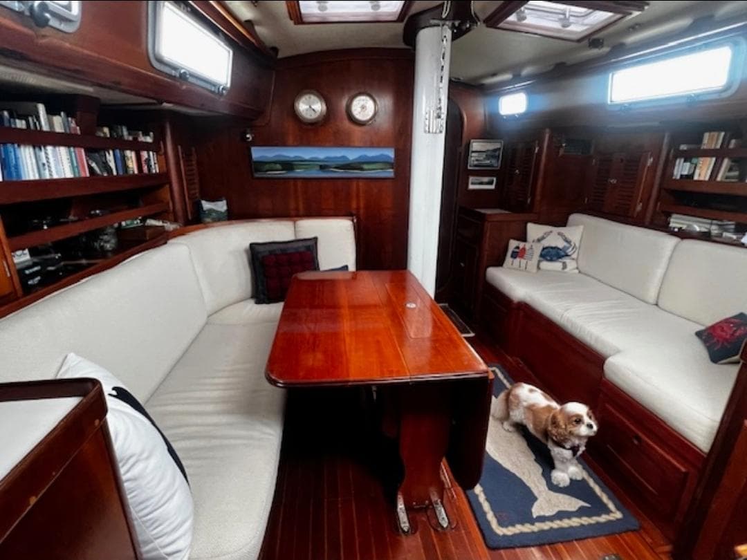 Cozy interior of a 1990 Bristol 47.7 Cutter/Sloop with wooden table and dog.