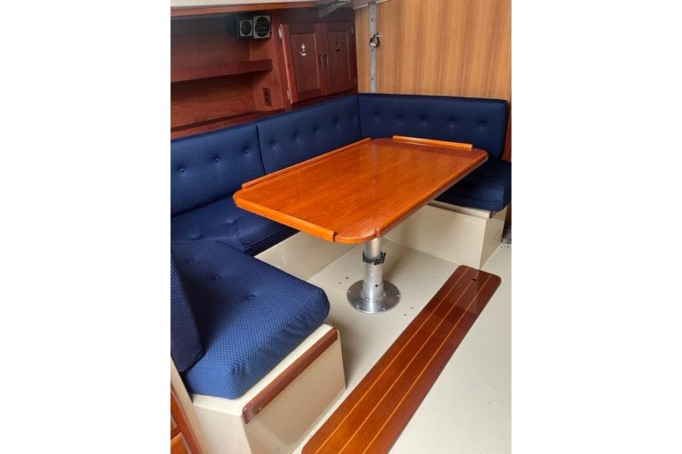 Interior of 1982 Catalina 38 sailboat with wooden table and blue cushioned seating.