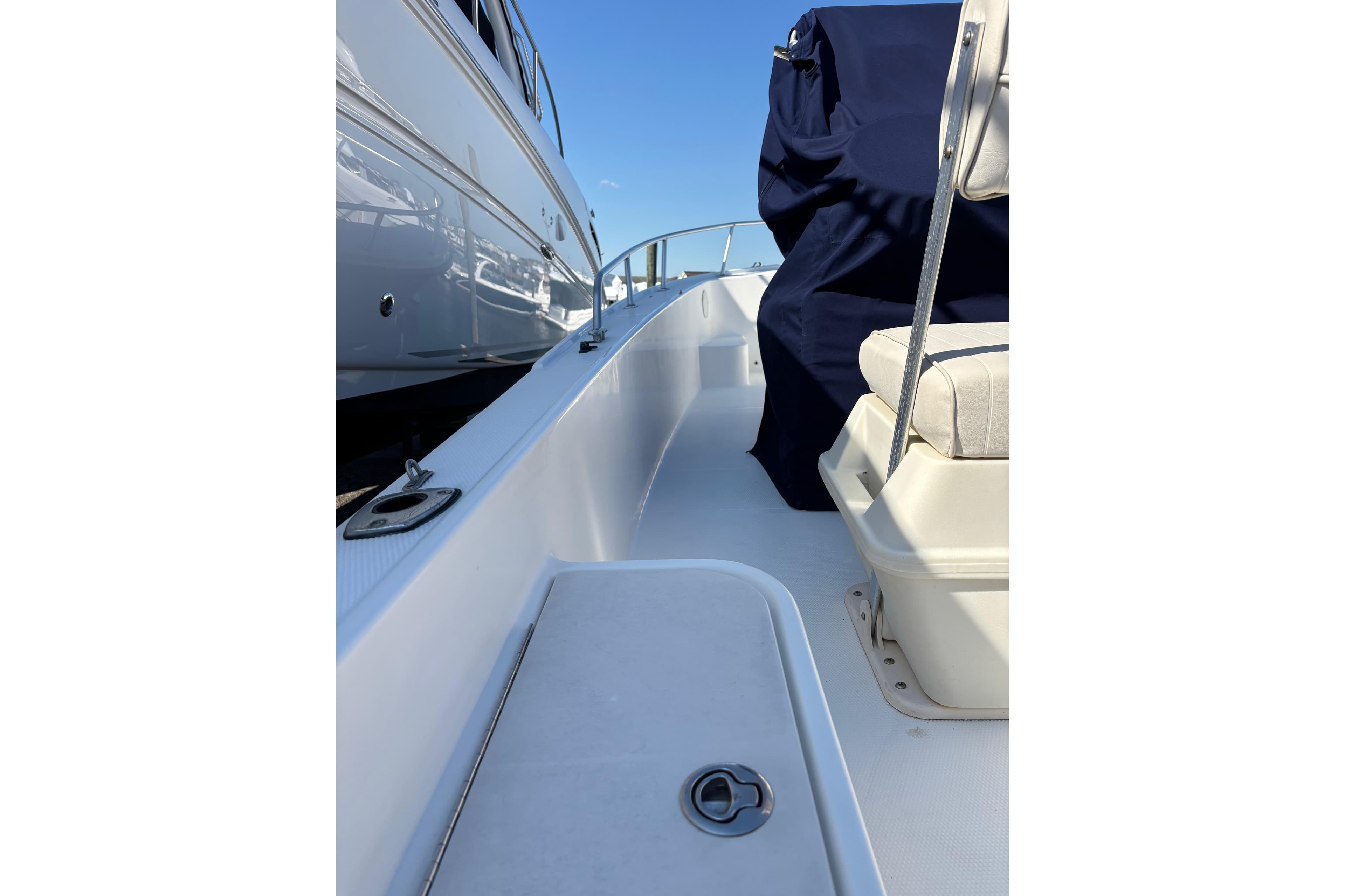 2006 Mako 171 Center Console boat deck with seating and railing, docked beside another vessel.