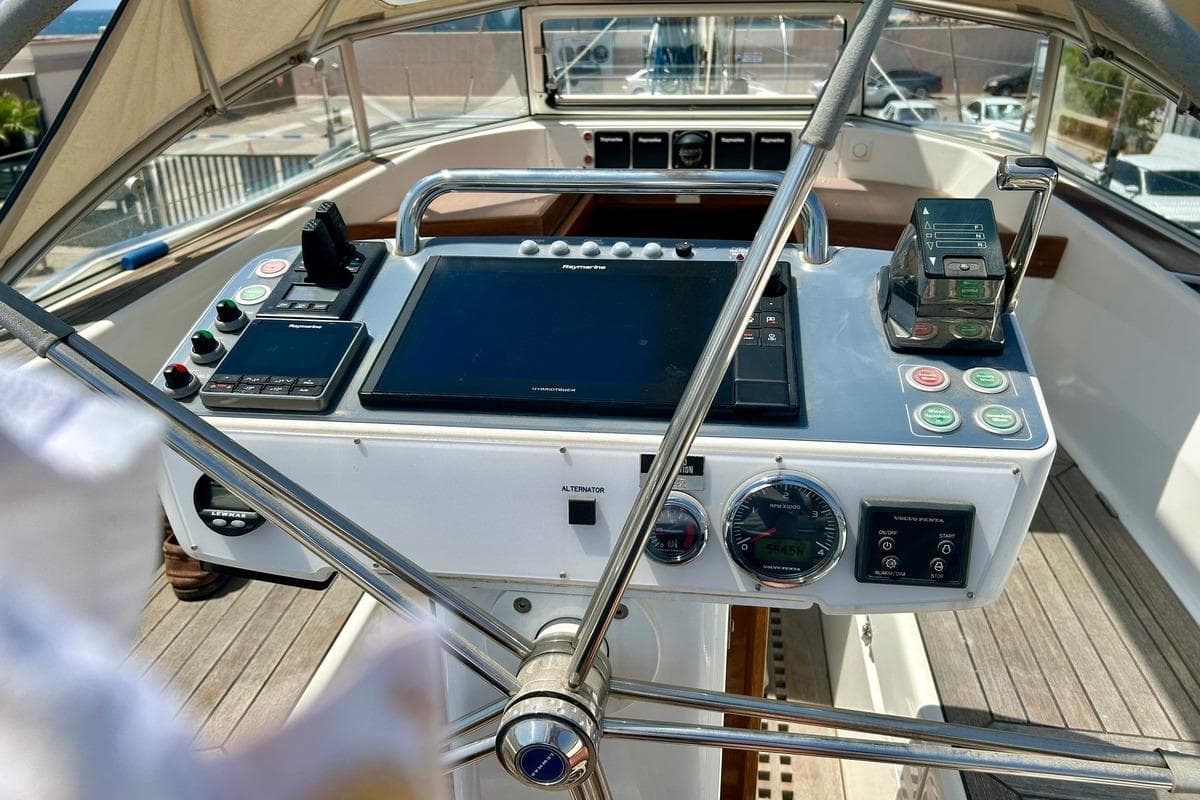 Cockpit of 2021 Hallberg-Rassy 44 sailboat with navigation instruments and steering wheel.