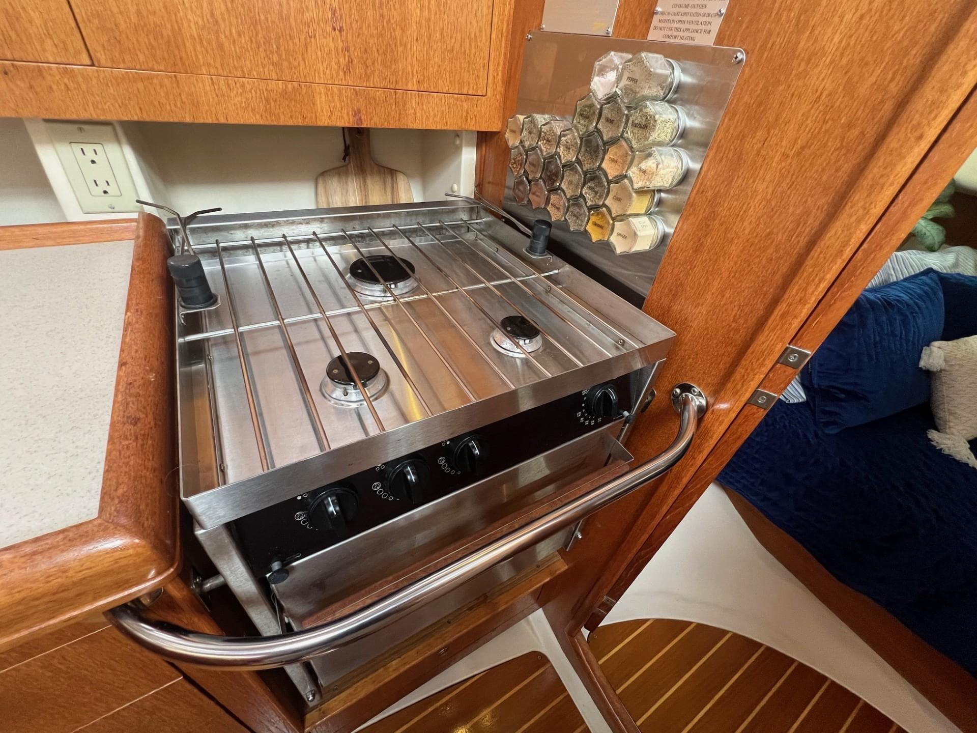 Compact kitchen stove in a 2002 Hunter 386 yacht, featuring a stainless steel finish.