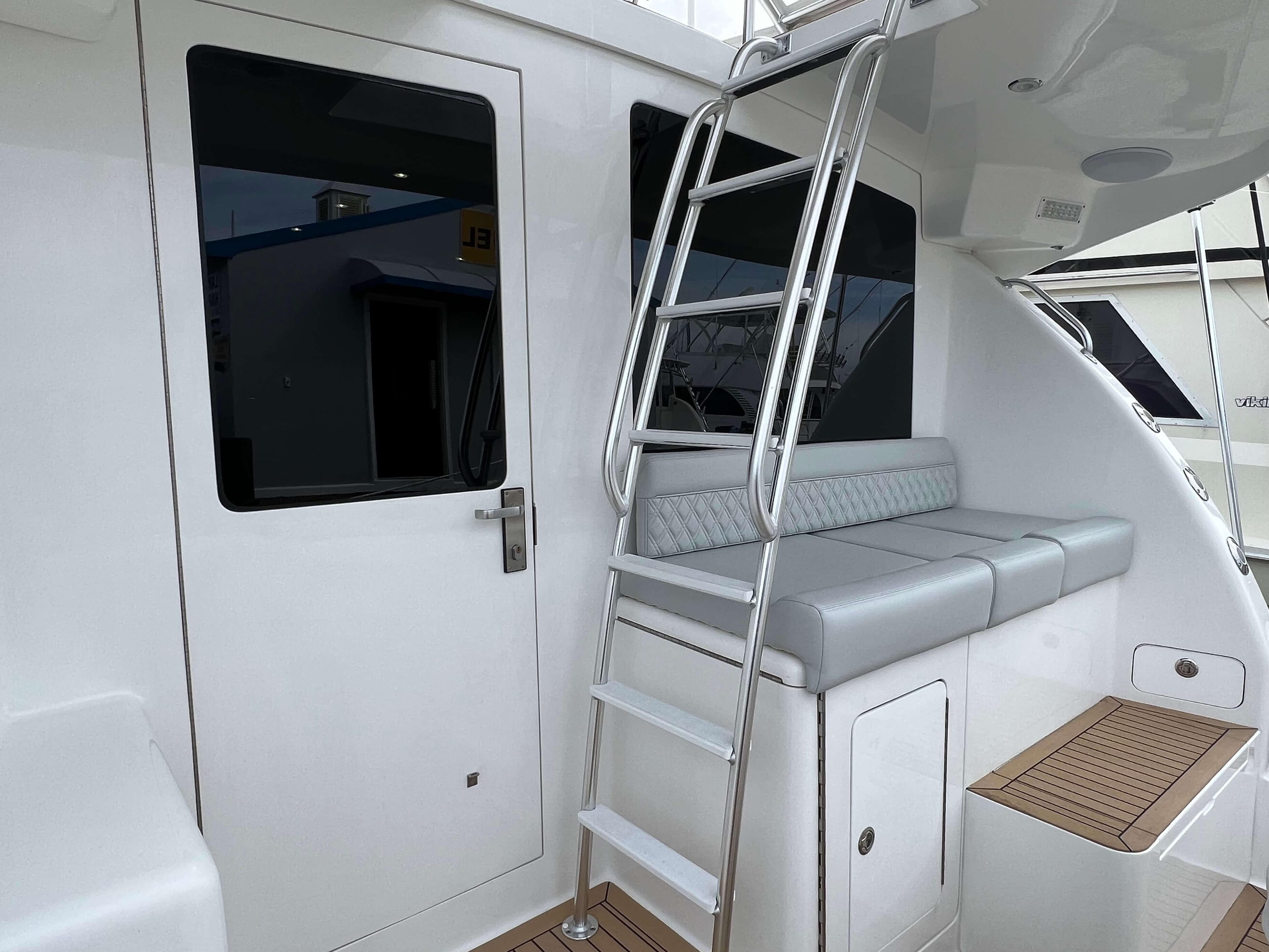 2025 Henriques 42 Flybridge yacht with ladder, cushioned seating, and sleek white exterior.
