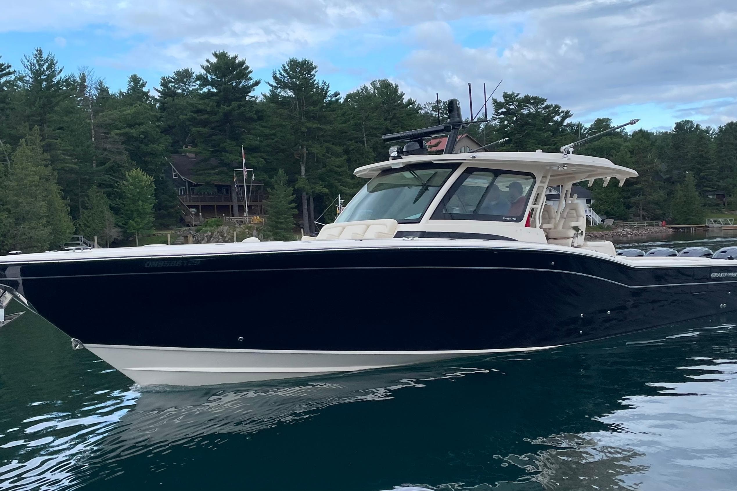 2023 Grady-White Canyon 456 boat on a serene lake with forested shoreline.