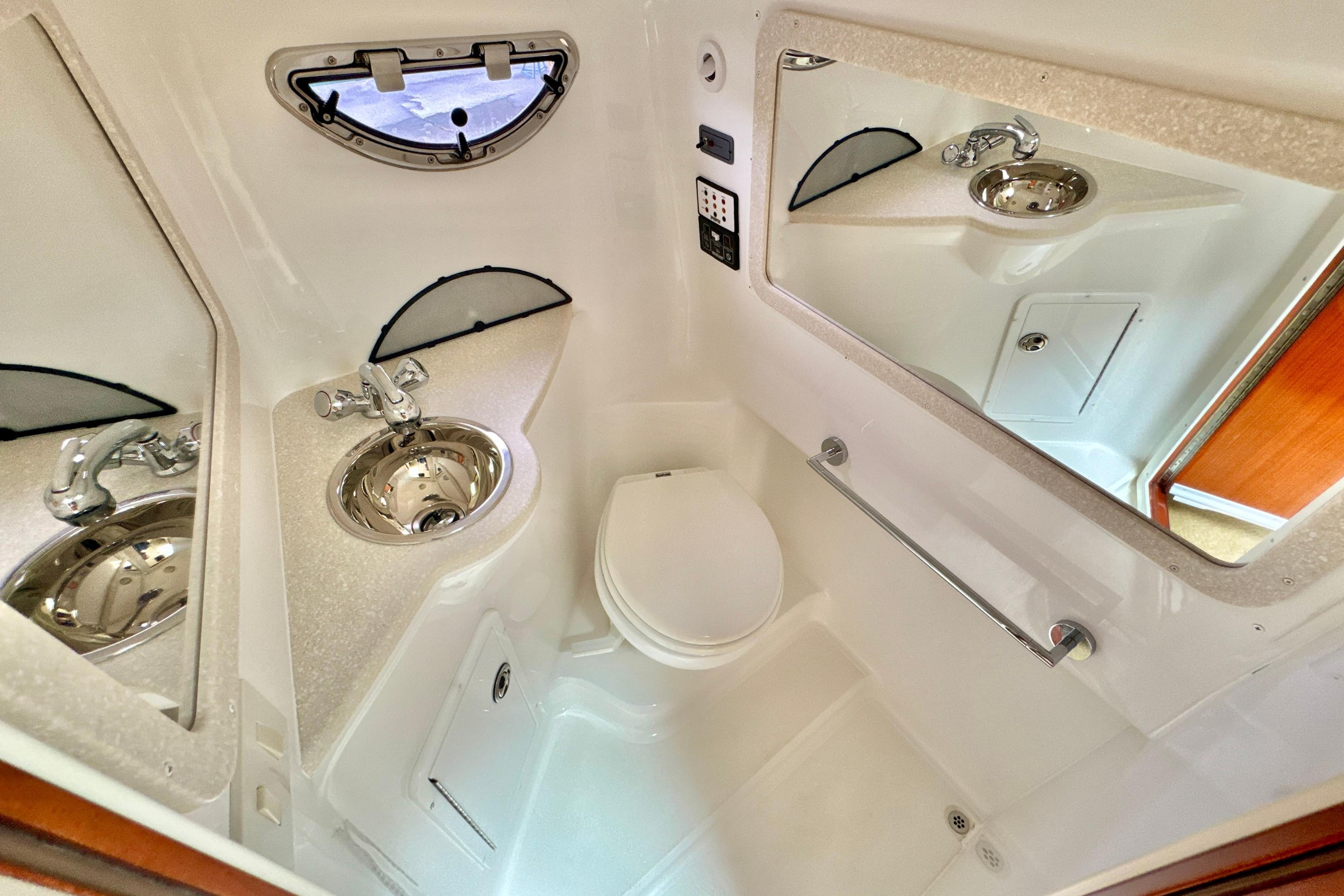 Compact bathroom in 2008 Cobalt 323 boat with sink, toilet, and mirror.