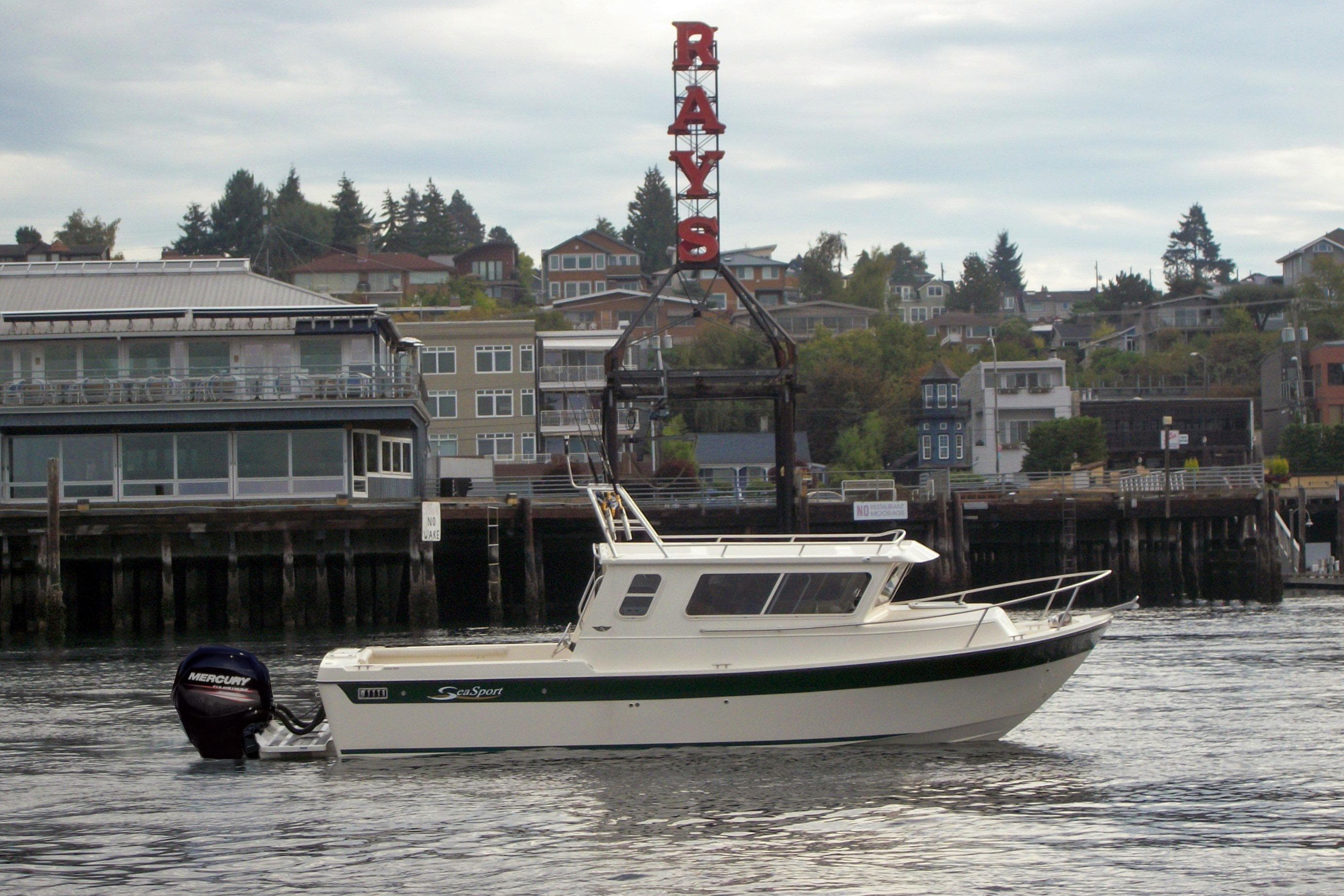 2026 Sea Sport Kodiak 2600 boat on water near waterfront buildings and "RAYS" sign.