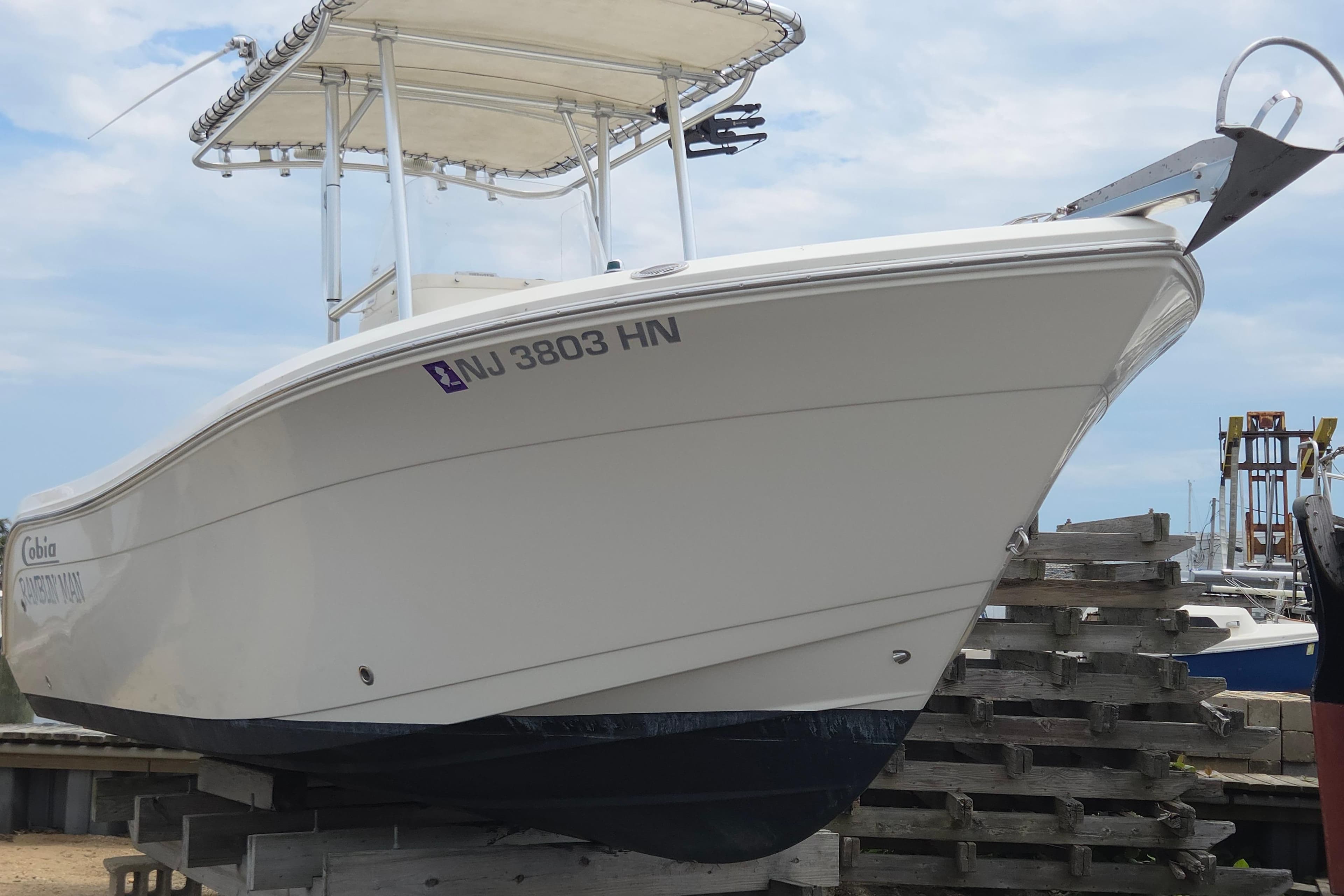 2014 Cobia 217 Center Console boat on dry dock, showcasing sleek design and registration number.