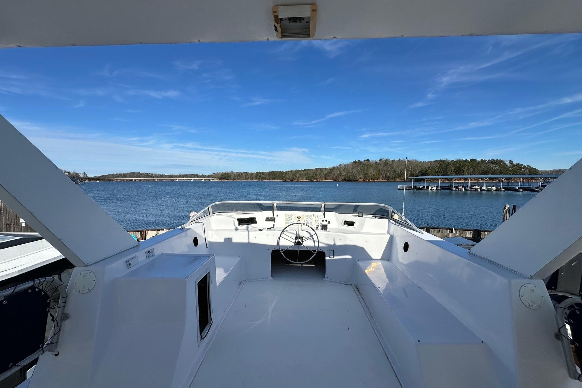 Helm of 2000 Sumerset 16x73 houseboat overlooking serene lake and marina.