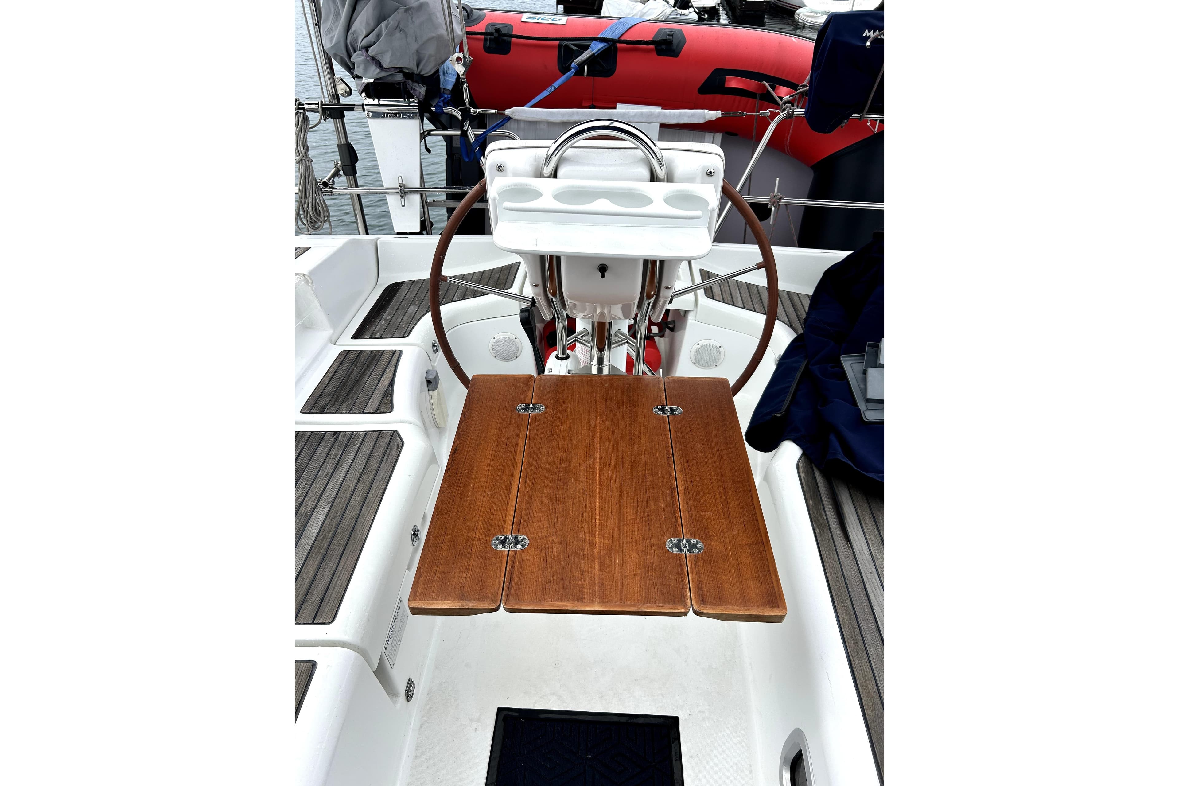 Cockpit of 2005 Beneteau Oceanis 373 sailboat with wooden table and steering wheel.