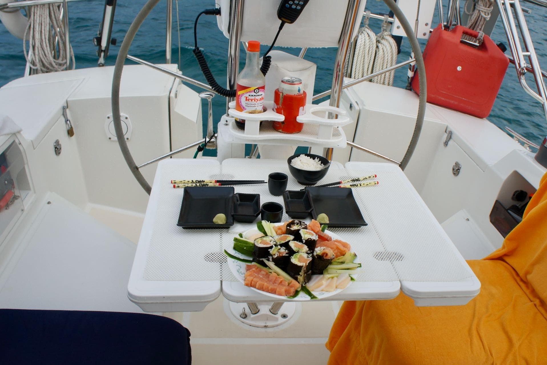 Sushi meal setup on a 2005 Outbound 46 yacht, featuring a steering wheel and ocean backdrop.