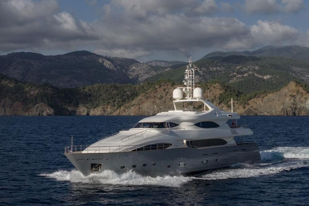 Luxurious CRN 129 yacht cruising near scenic mountainous coastline, 2009 model.