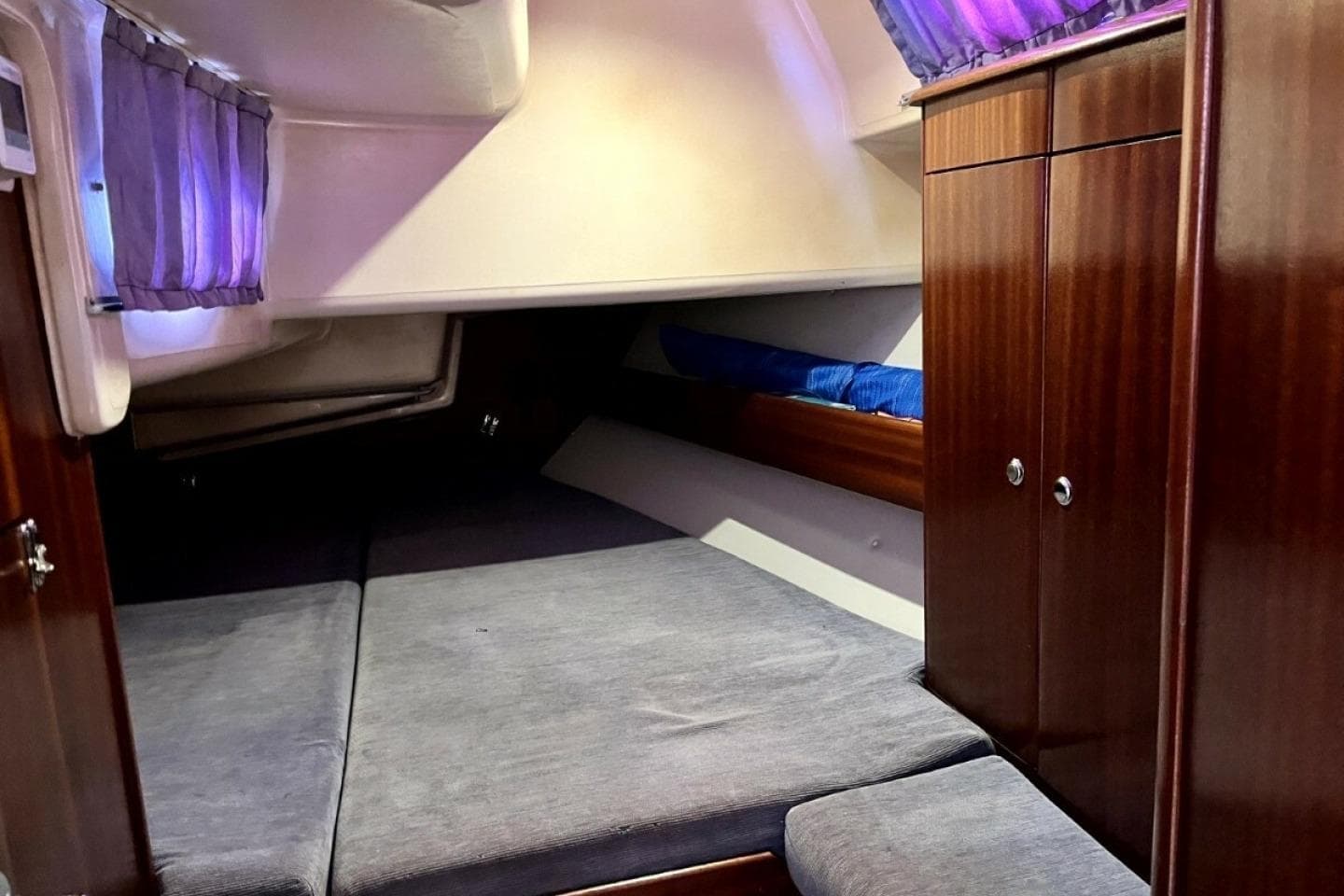 Cozy cabin interior of 2003 Bavaria 44 yacht with wooden cabinets and soft lighting.