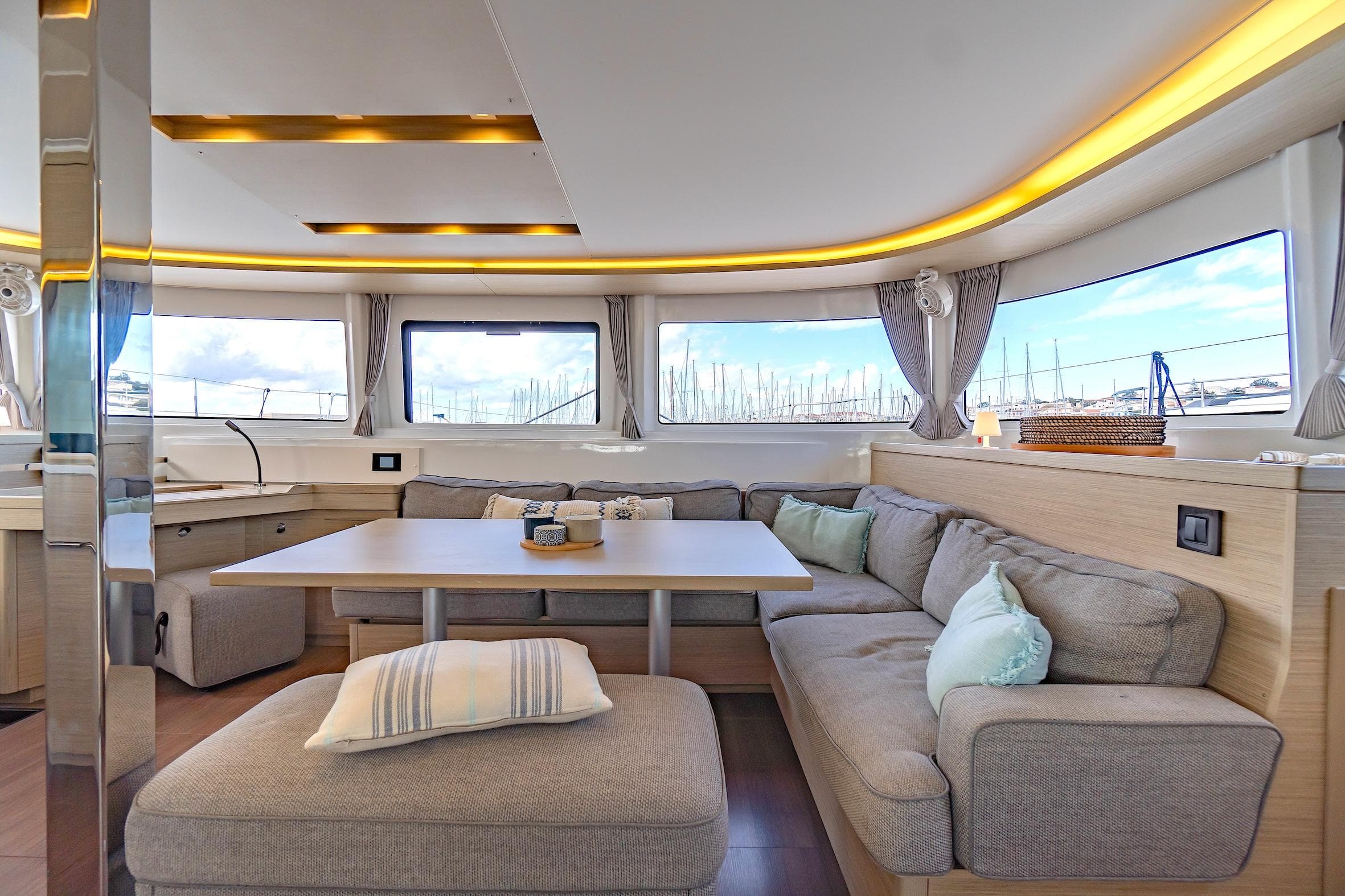Luxurious interior of 2023 Lagoon 46 catamaran with modern seating and panoramic windows.