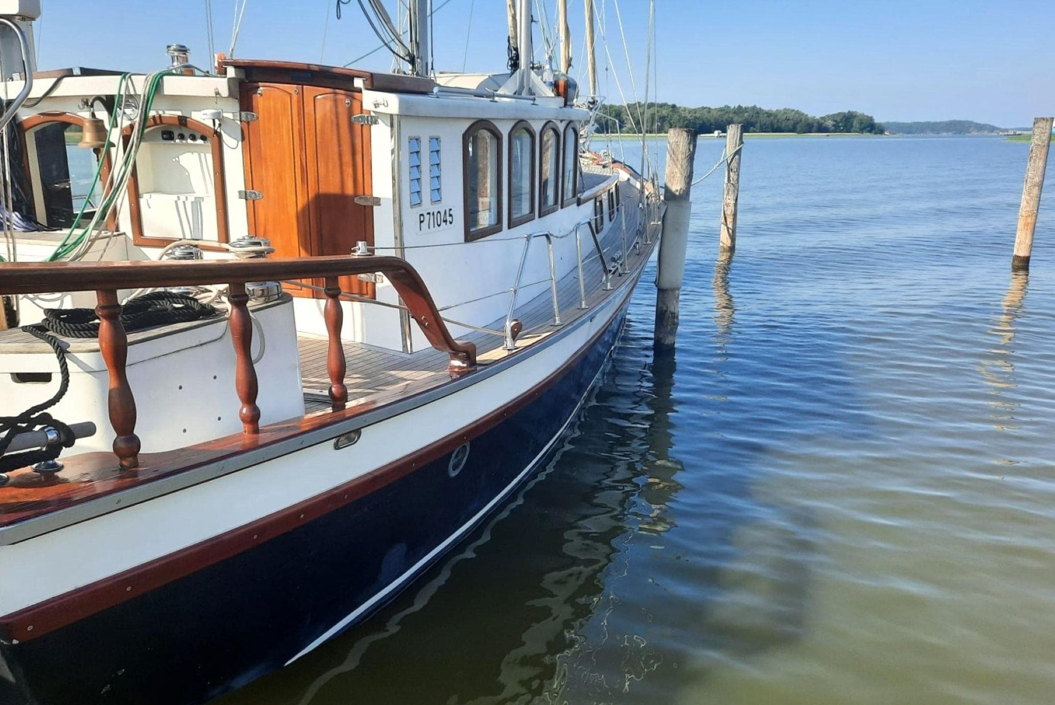 Vintage 1970 Schooner 43 docked on calm water, showcasing classic wooden design.