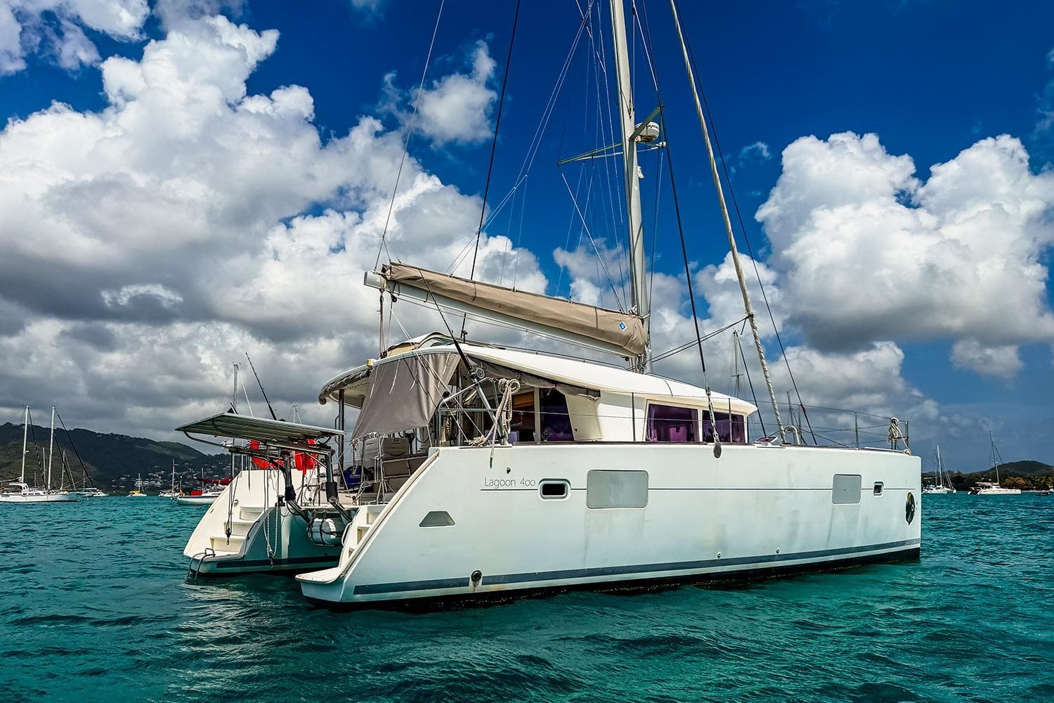 2010 Lagoon 400 catamaran sailing on turquoise waters under a cloudy sky.