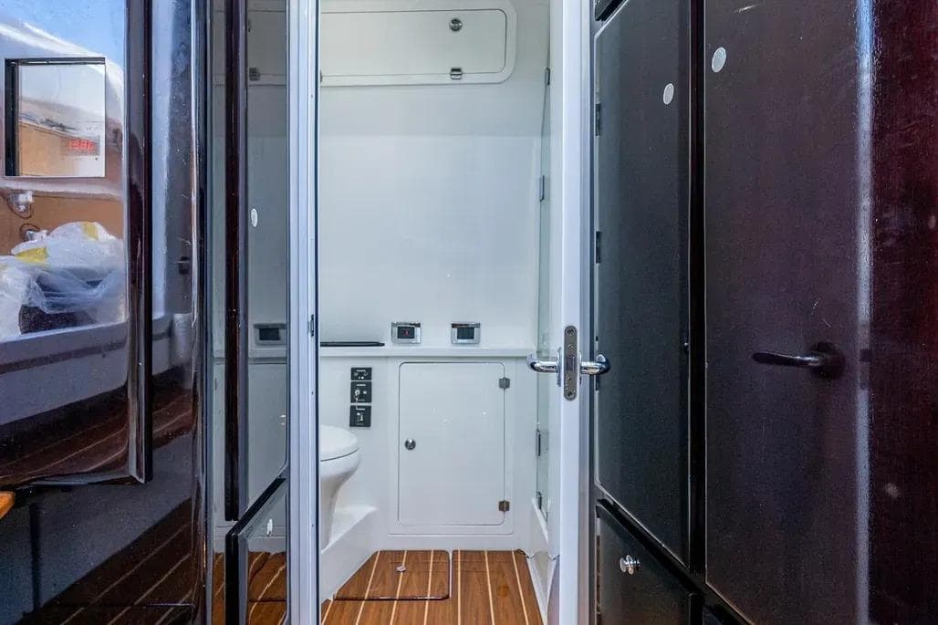 Interior of 2020 HCB 53 Sueños boat featuring a compact bathroom with wooden flooring.