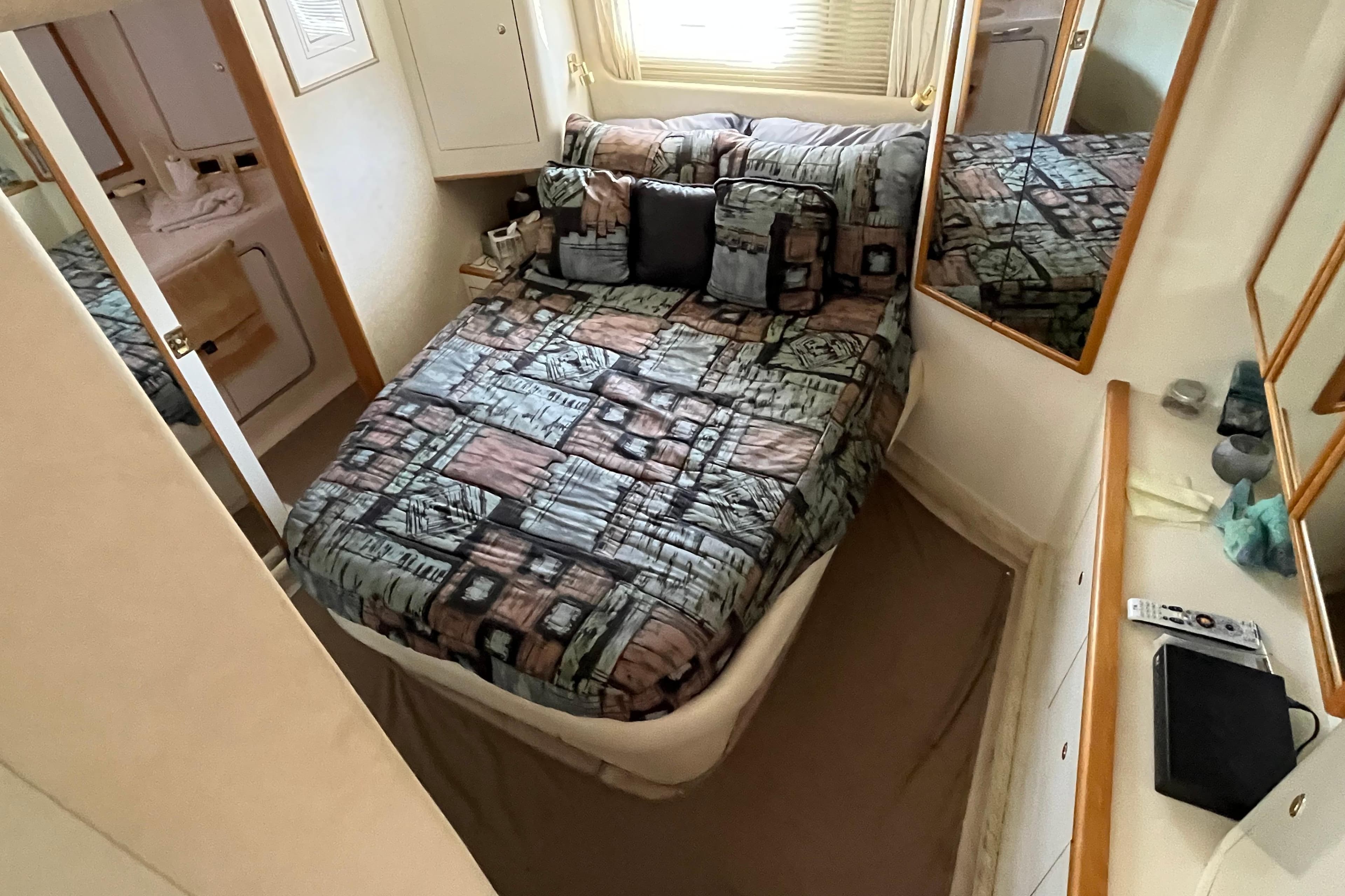 1997 Sea Ray 420 Aft Cabin bedroom with patterned bedding and mirrored walls.