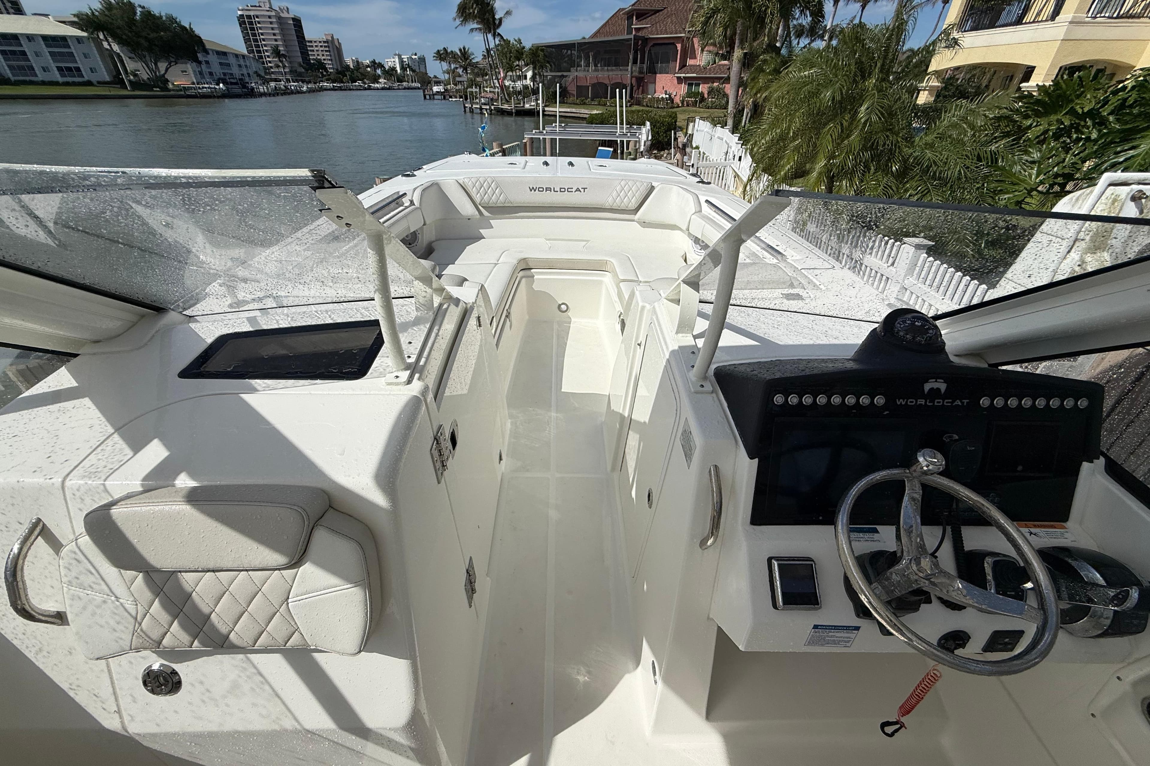 2025 World Cat 280 DC-X boat interior with steering wheel and waterfront view.