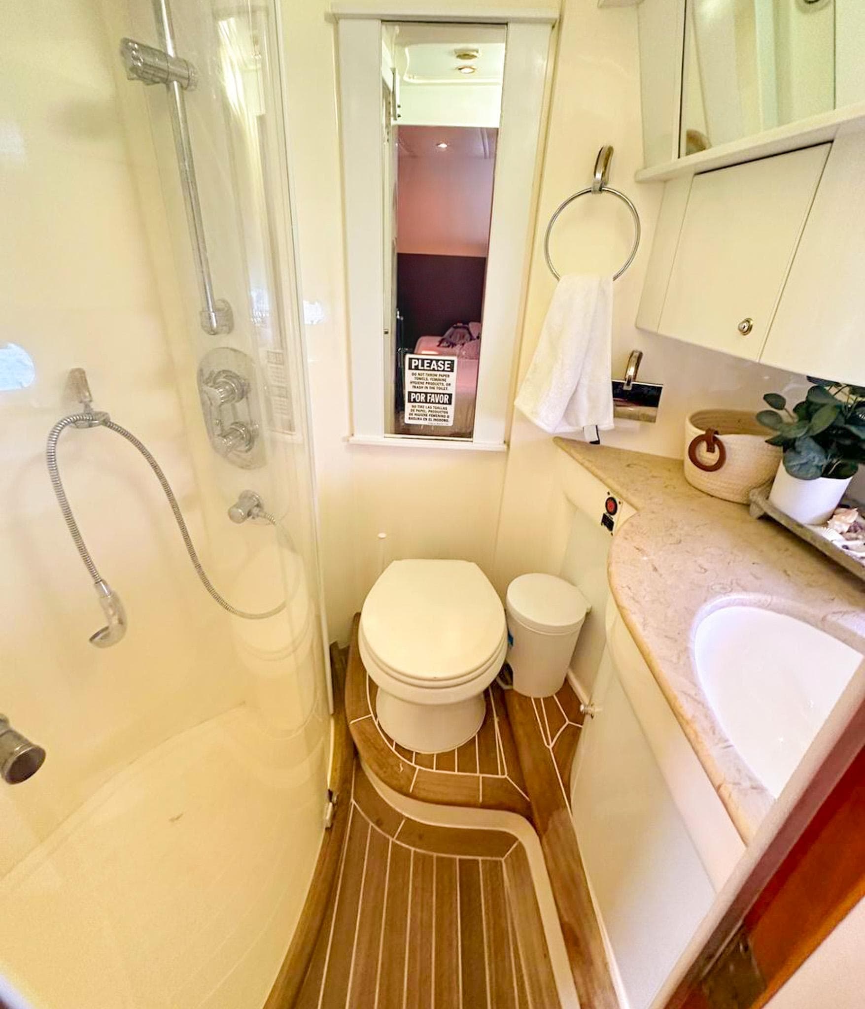 2004 Sealine 47 yacht bathroom with shower, toilet, sink, and wooden flooring.