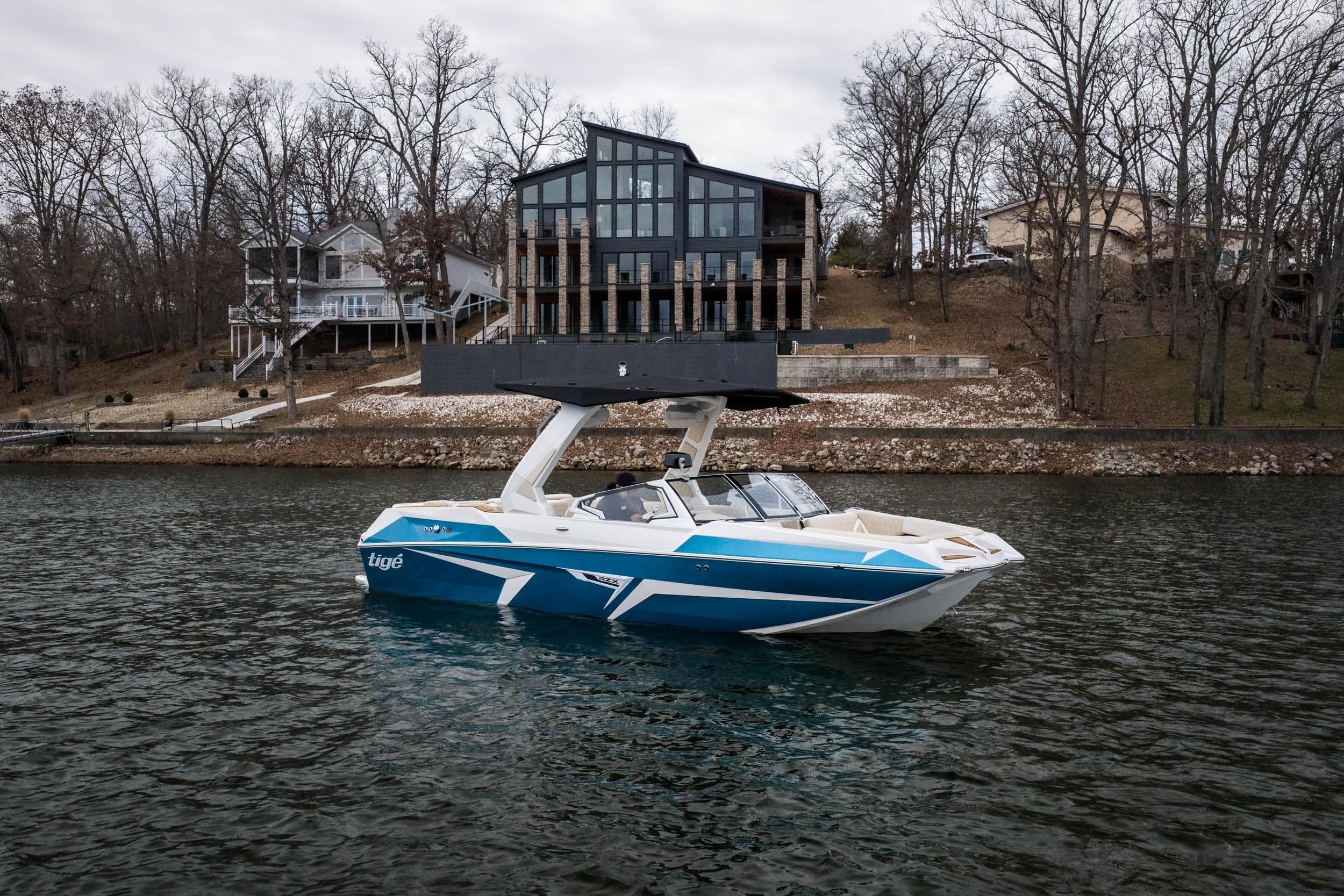 2026 Tigé 22RZX boat on a lake with modern lakeside homes in the background.