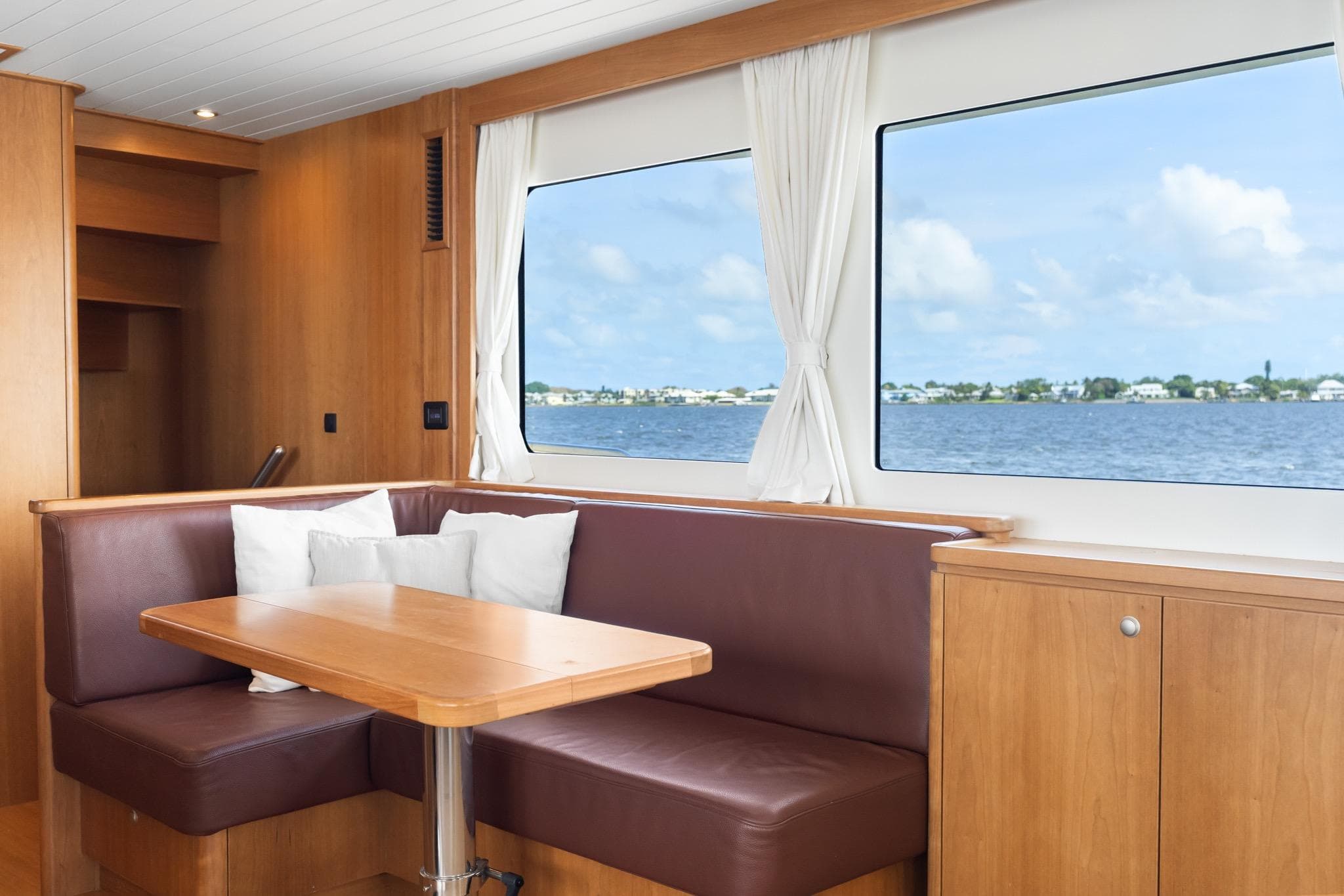 Interior of 2022 Alm Trawler Delfino 64 with dining area and scenic window view.