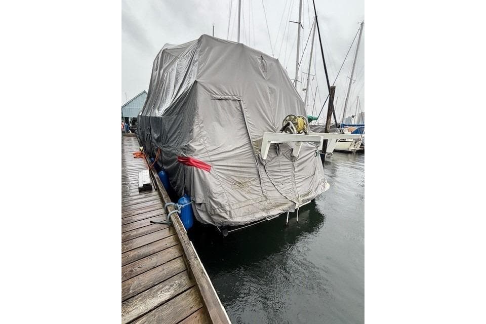 1983 Canoe Cove Sedan Bridge covered at marina dock on a rainy day.
